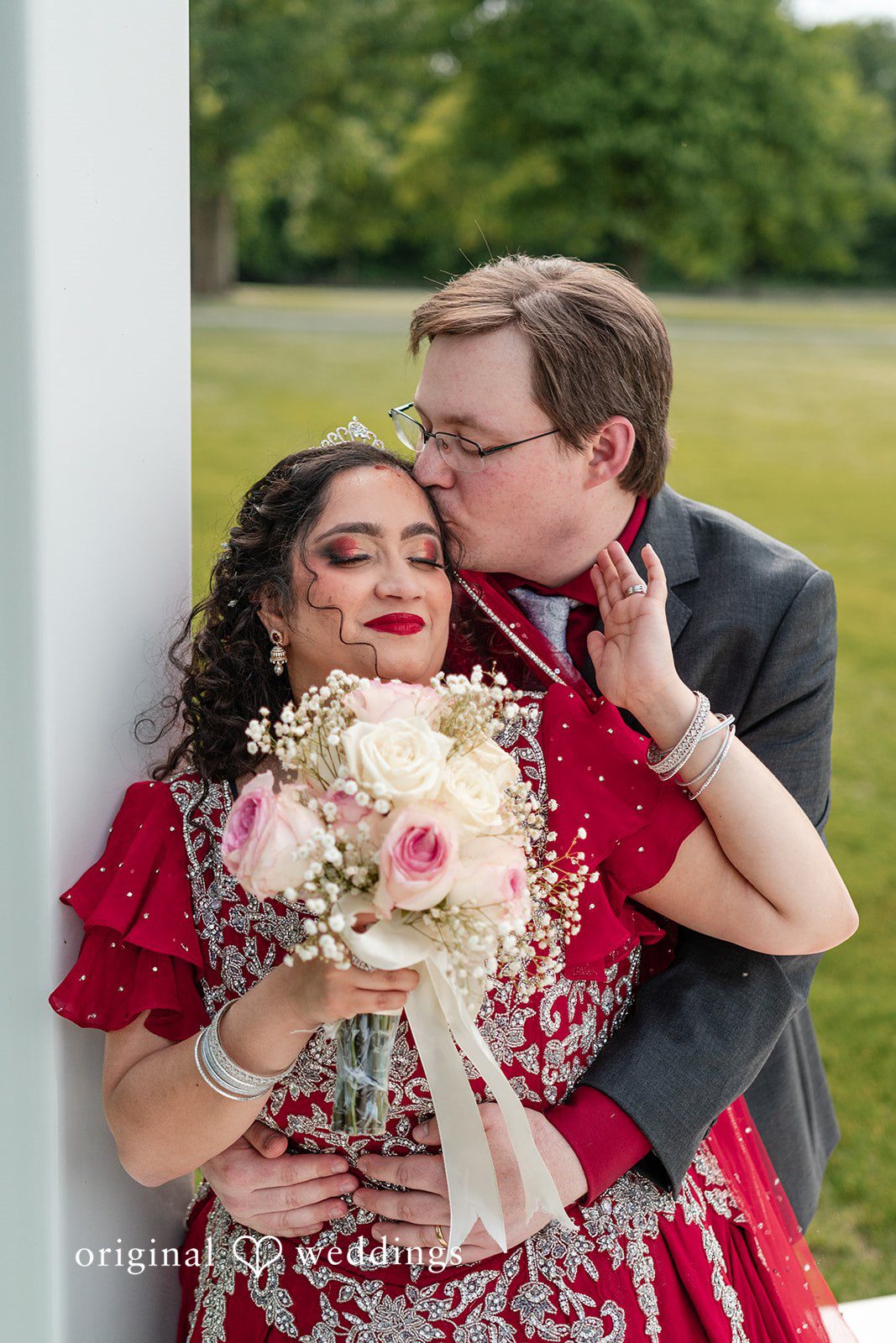 Anthony + Simi A groom kissing a bride while she holds a bouquet.