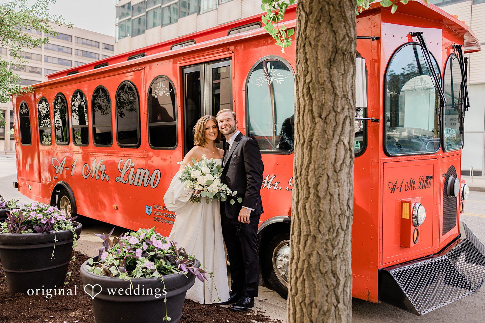 Luke + Madison Bride and groom posing beside the wedding trolley at St. Clair Ballroom captured by Cleveland Wedding Photographers from Original Weddings.