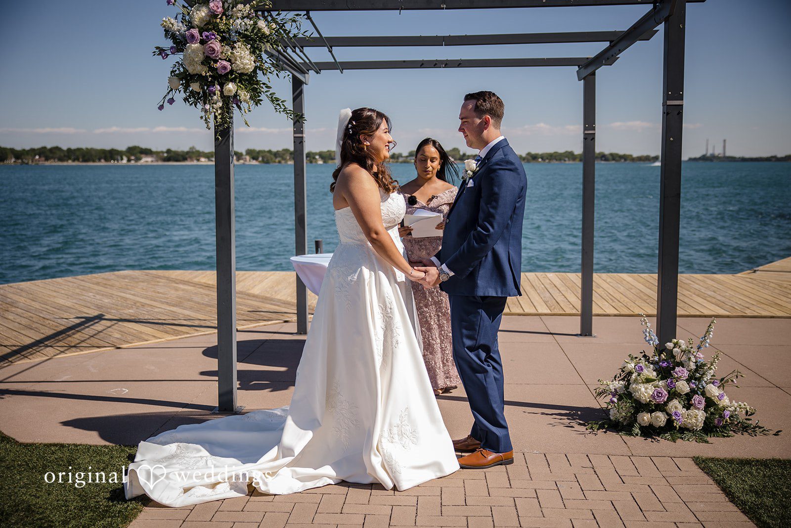 James + Nora Bride and groom sharing eye contact while smiling before priest at St. Clair Inn