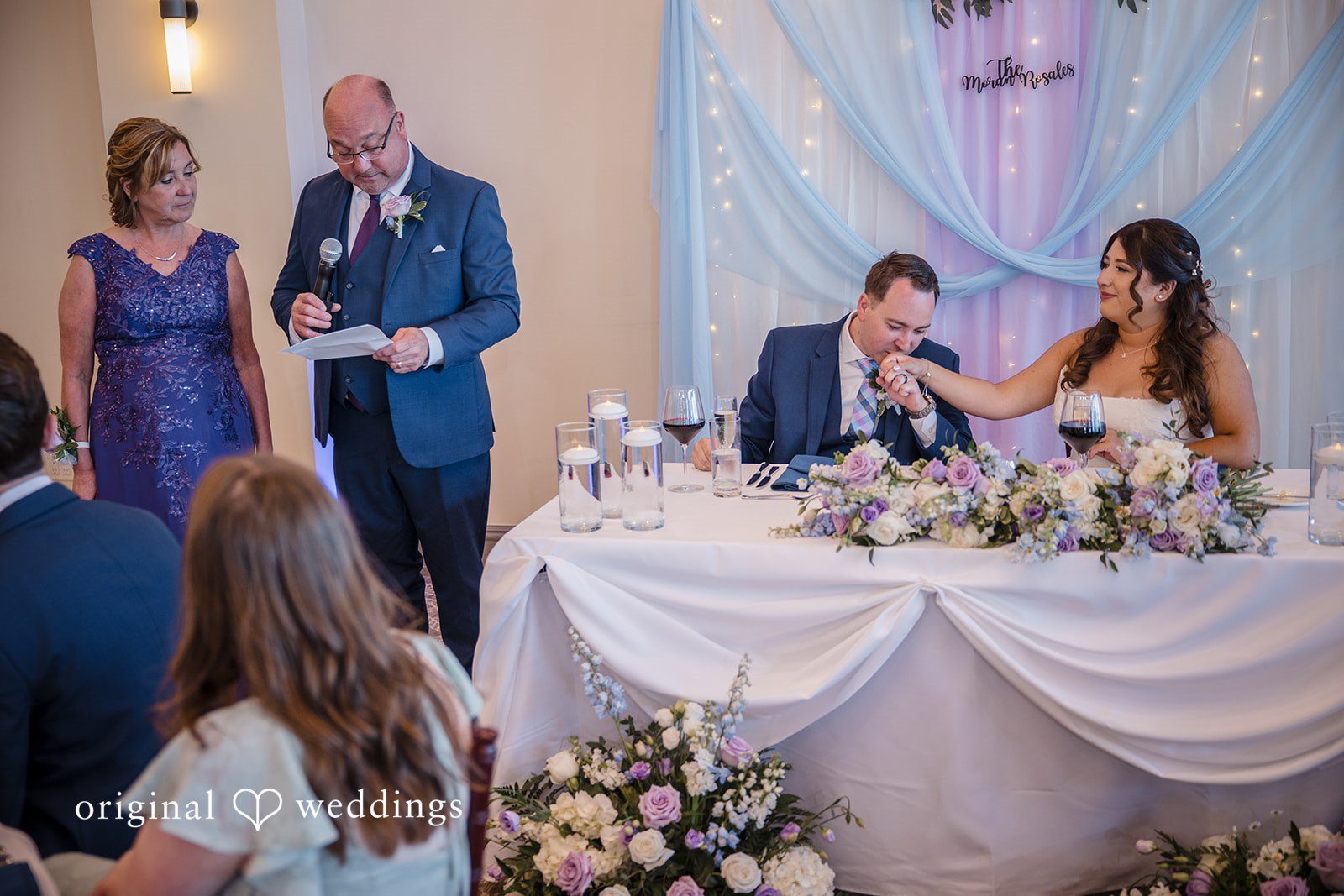 James + Nora Groom kissing the bride's hand at the reception table at St. Clair Inn