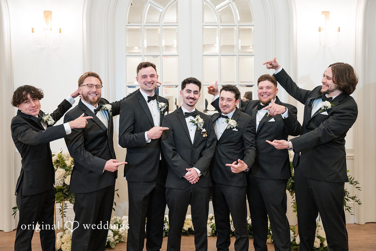 Groom posing with his groomsmen in matching black tuxedos before the ceremony