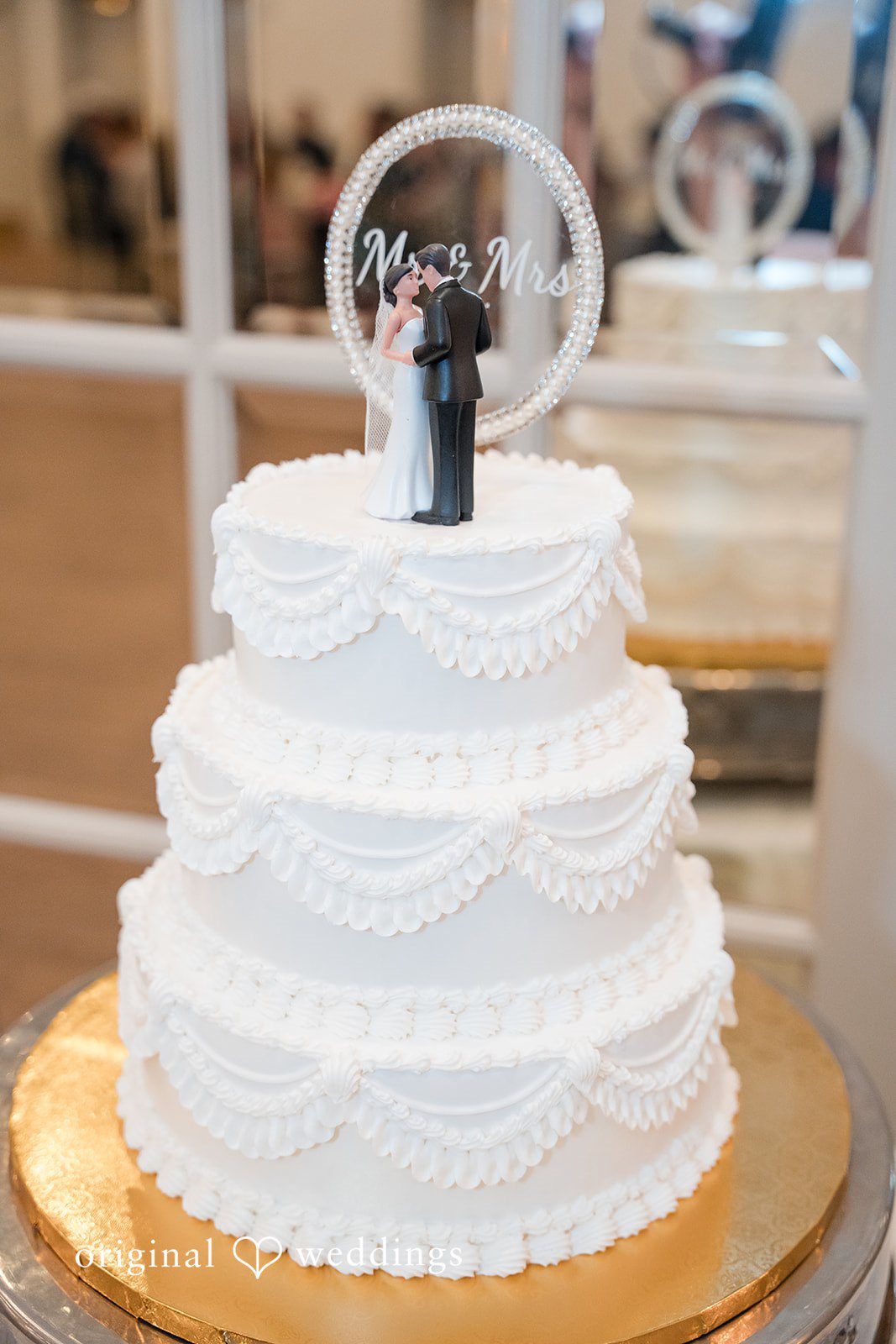 Classic three-tier white wedding cake featuring a bride and groom cake topper