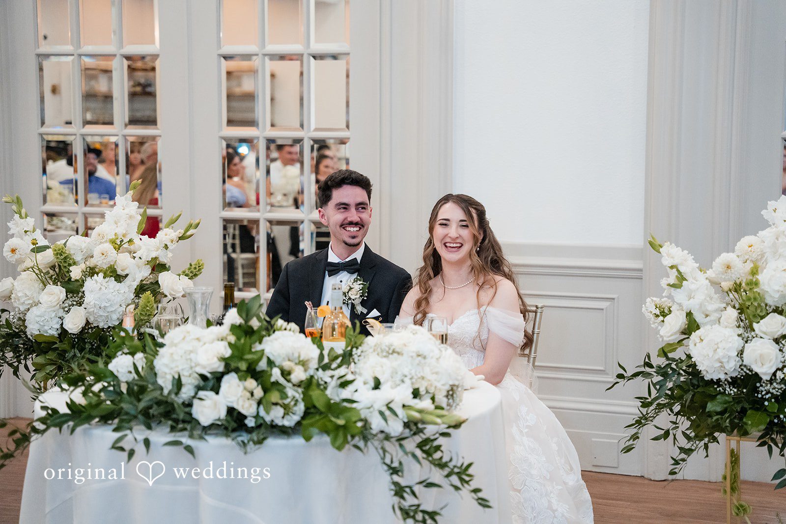 Newlyweds smiling at their sweetheart table at Sterling Hotel captured by Sacramento Wedding Photographers from Original Weddings.