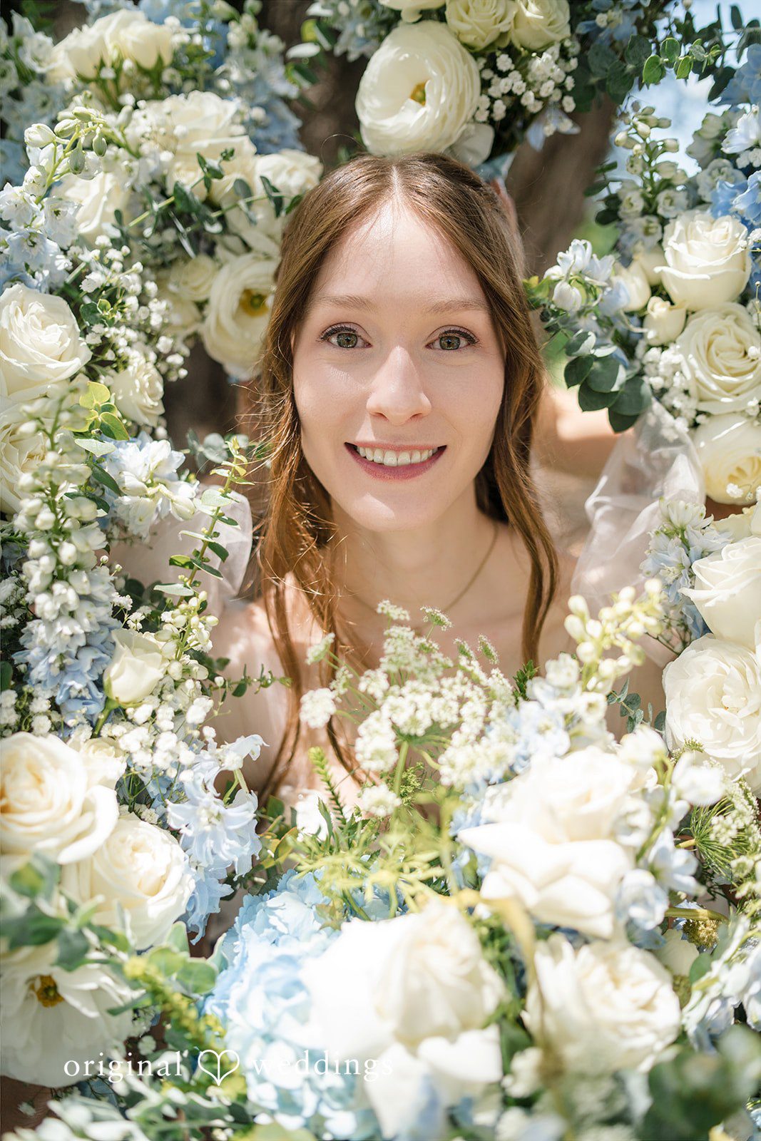 Morgan + Luke A smiling bride looks directly ahead surrounded by a lush bouquet.