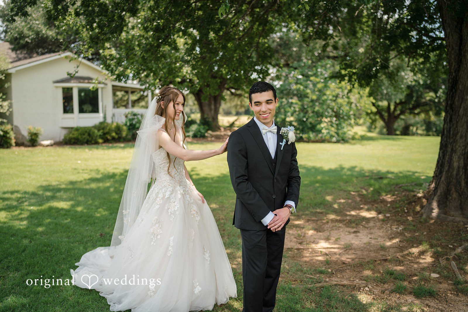 Morgan + Luke A bride walks toward a groom standing in a grassy area near a house.