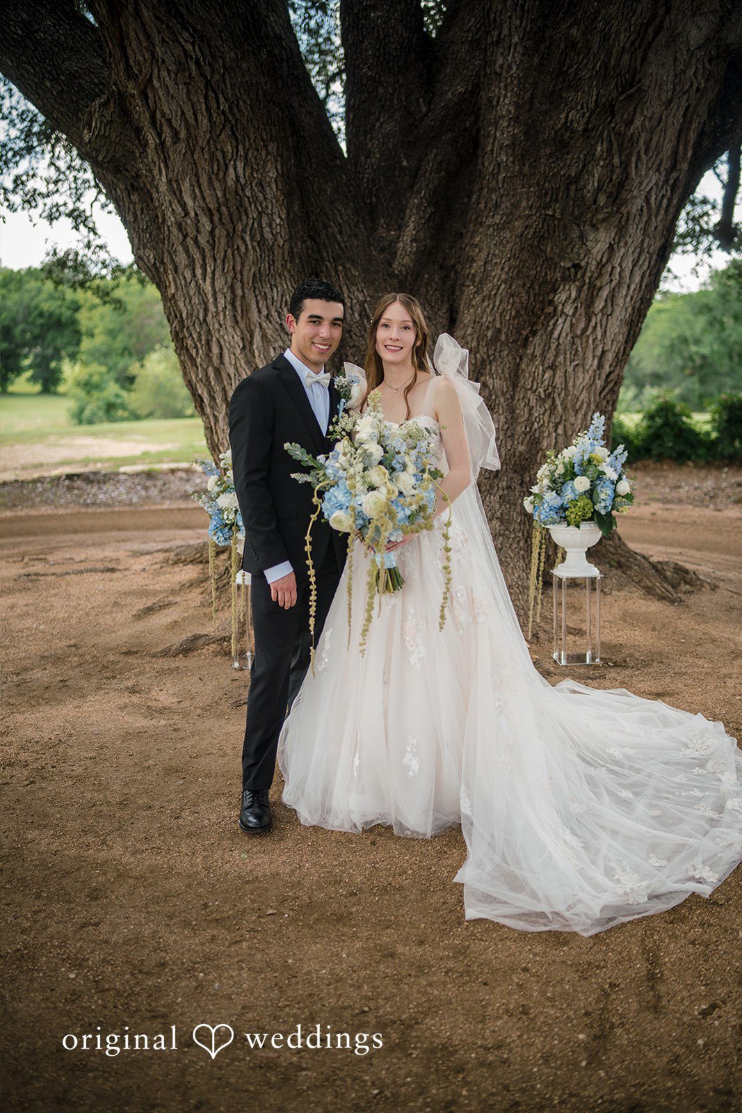 Morgan + Luke A bride and groom pose together under the shade of a large tree.