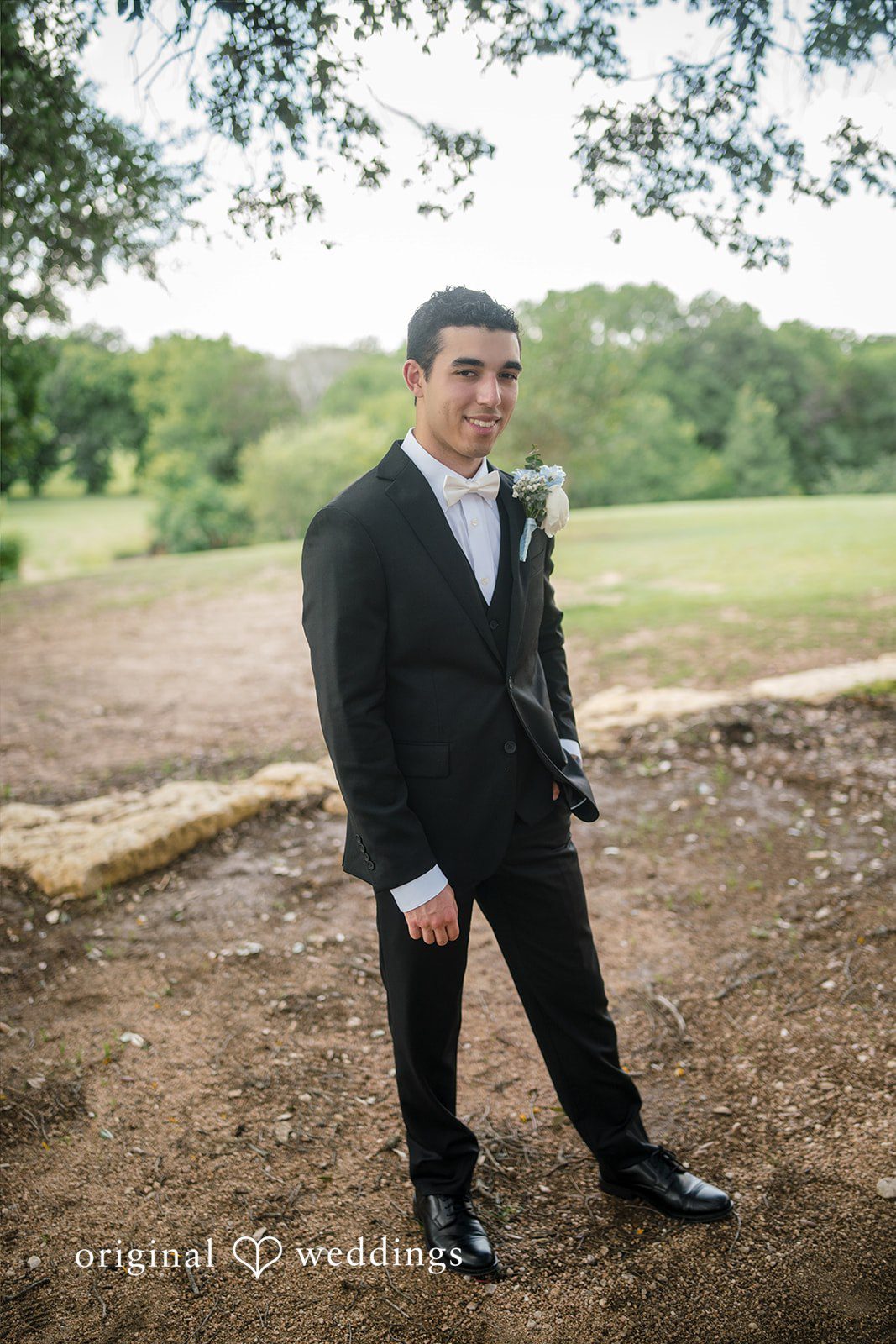 Morgan + Luke A groom poses in a black suit on a grassy lawn at Stonebridge Wedding & Event Venue.