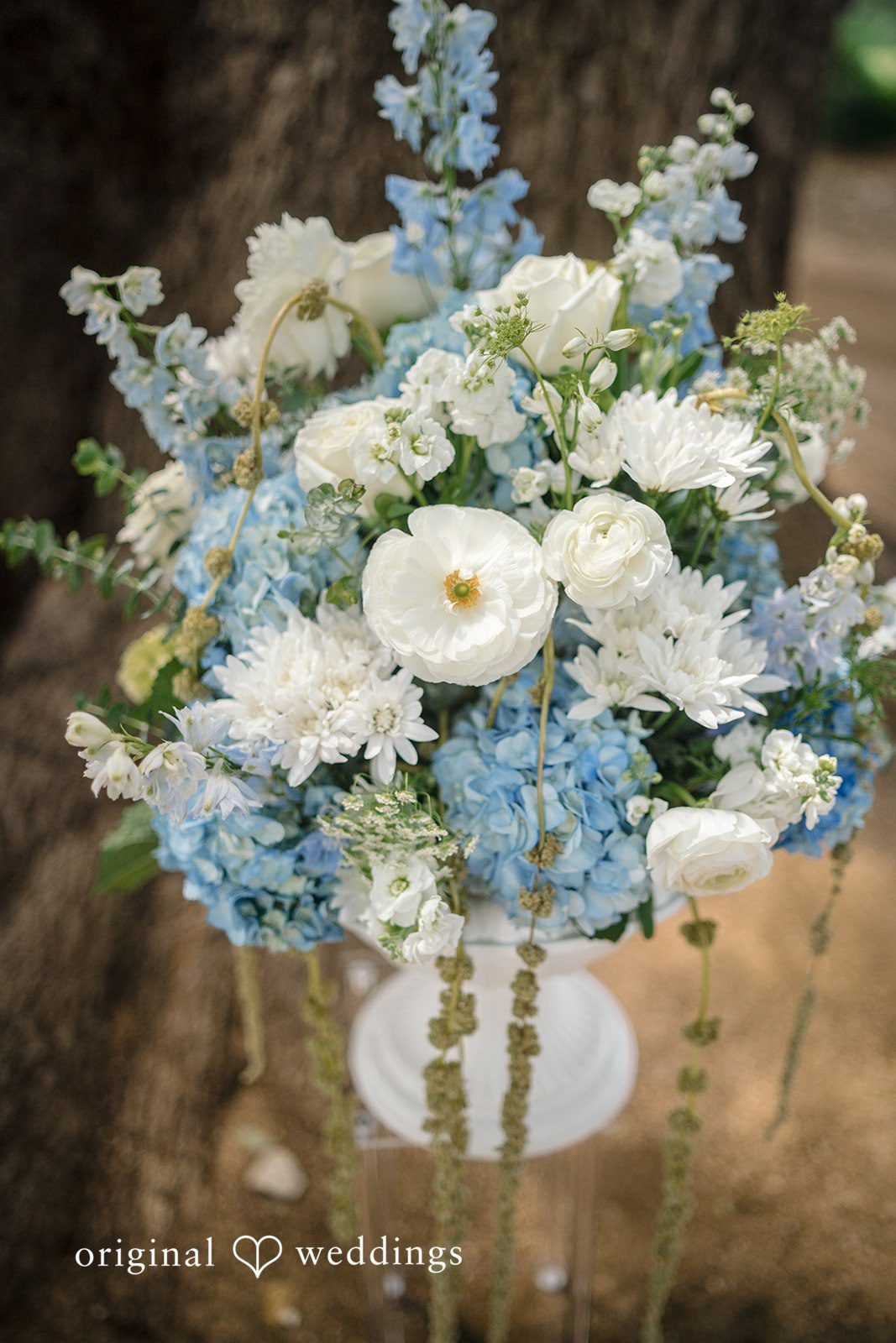 Morgan + Luke A lush wedding floral arrangement features white roses and blue hydrangeas.