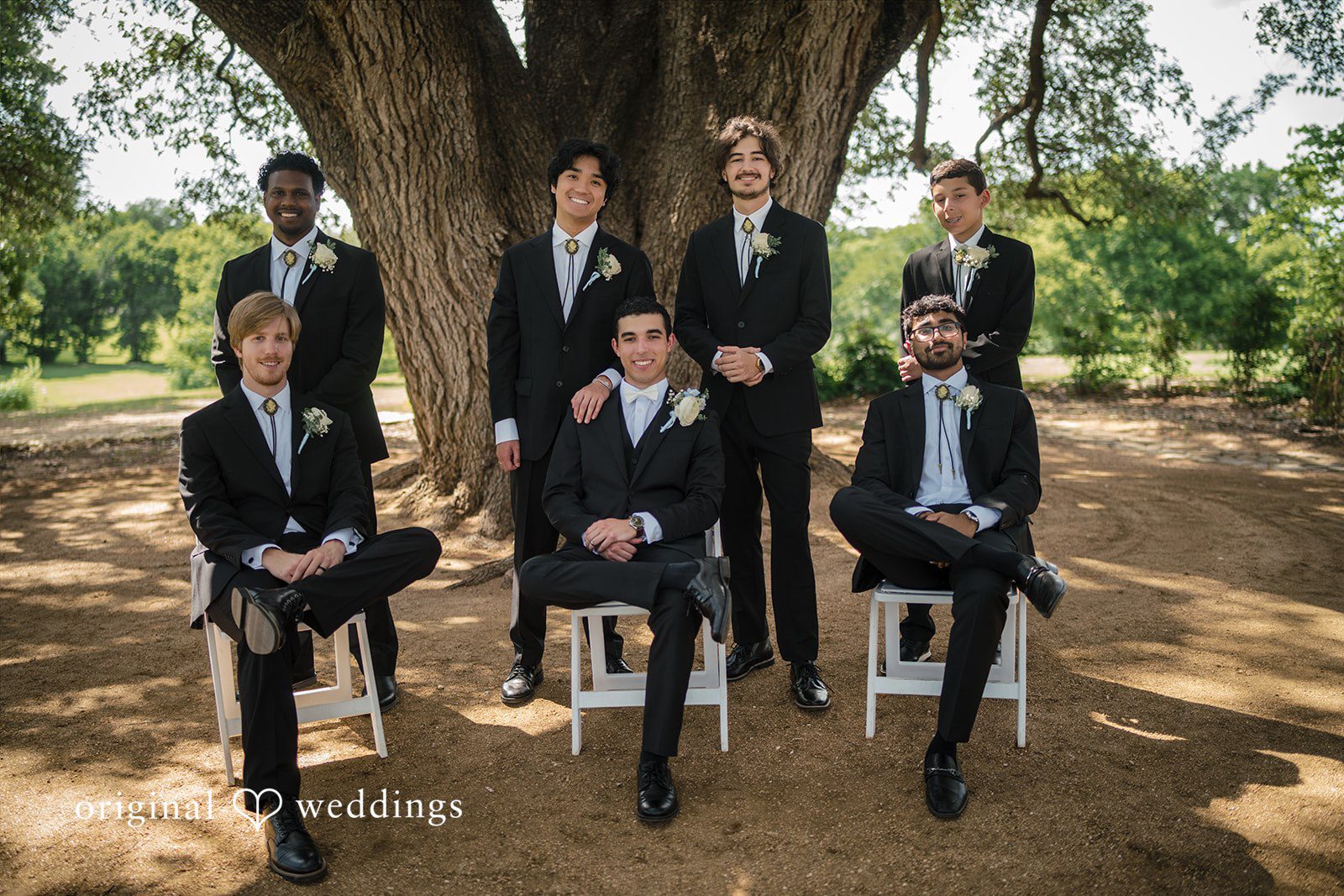 Morgan + Luke A groom poses seated with his groomsmen dressed in black suits.
