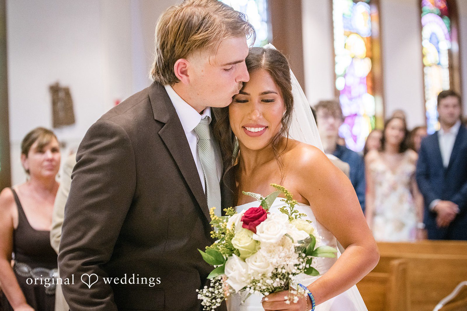 Groom hugging the bride and kissing her forehead at San Pedro Catholic Church