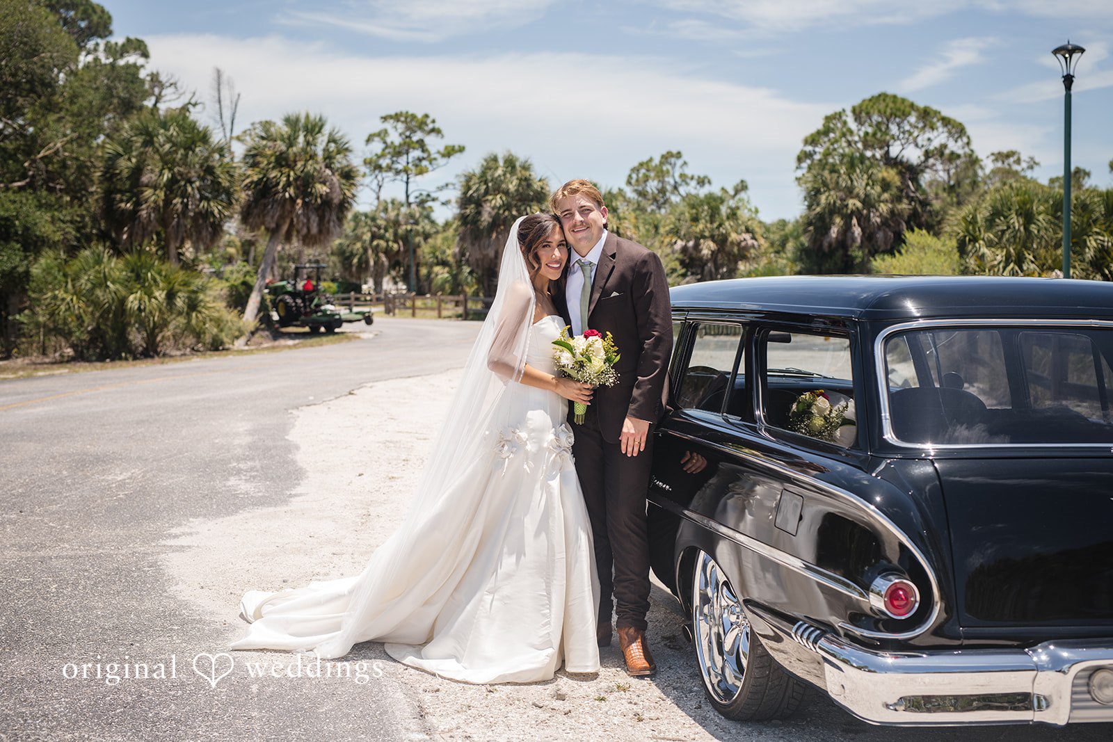 Tampa Wedding Photographers capturing couple photoshoot with the wedding car at San Pedro Catholic Church by Original Weddings