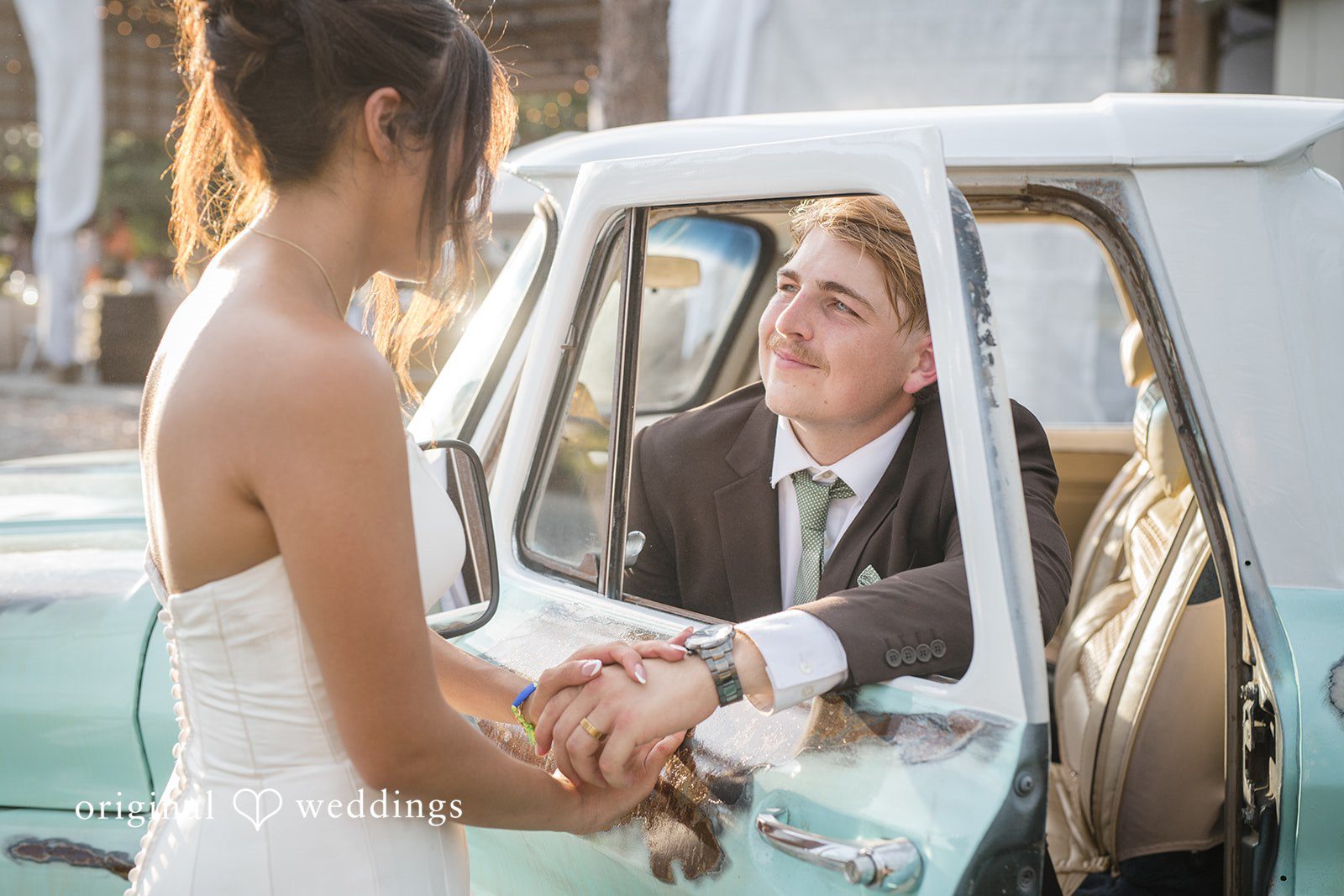 Groom sitting inside the car while the bride stands outside holding his hand at San Pedro Catholic Church