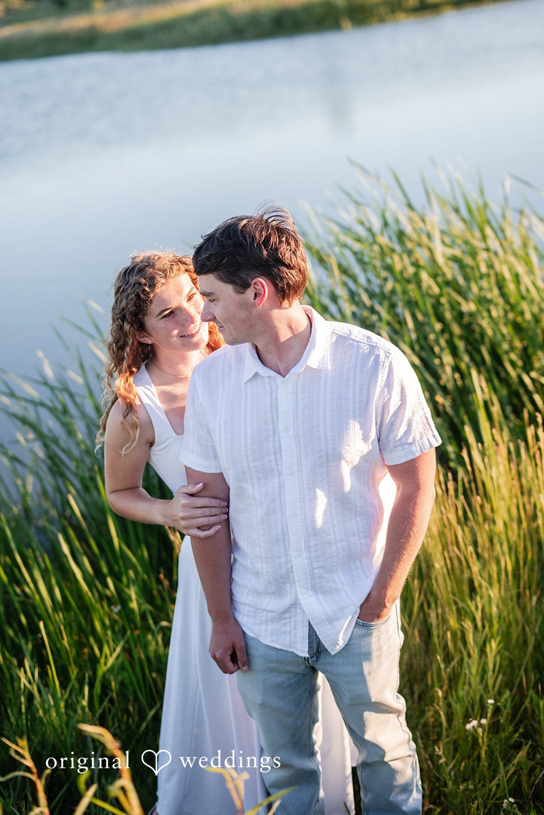 Couple standing together surrounded by tall green reeds.