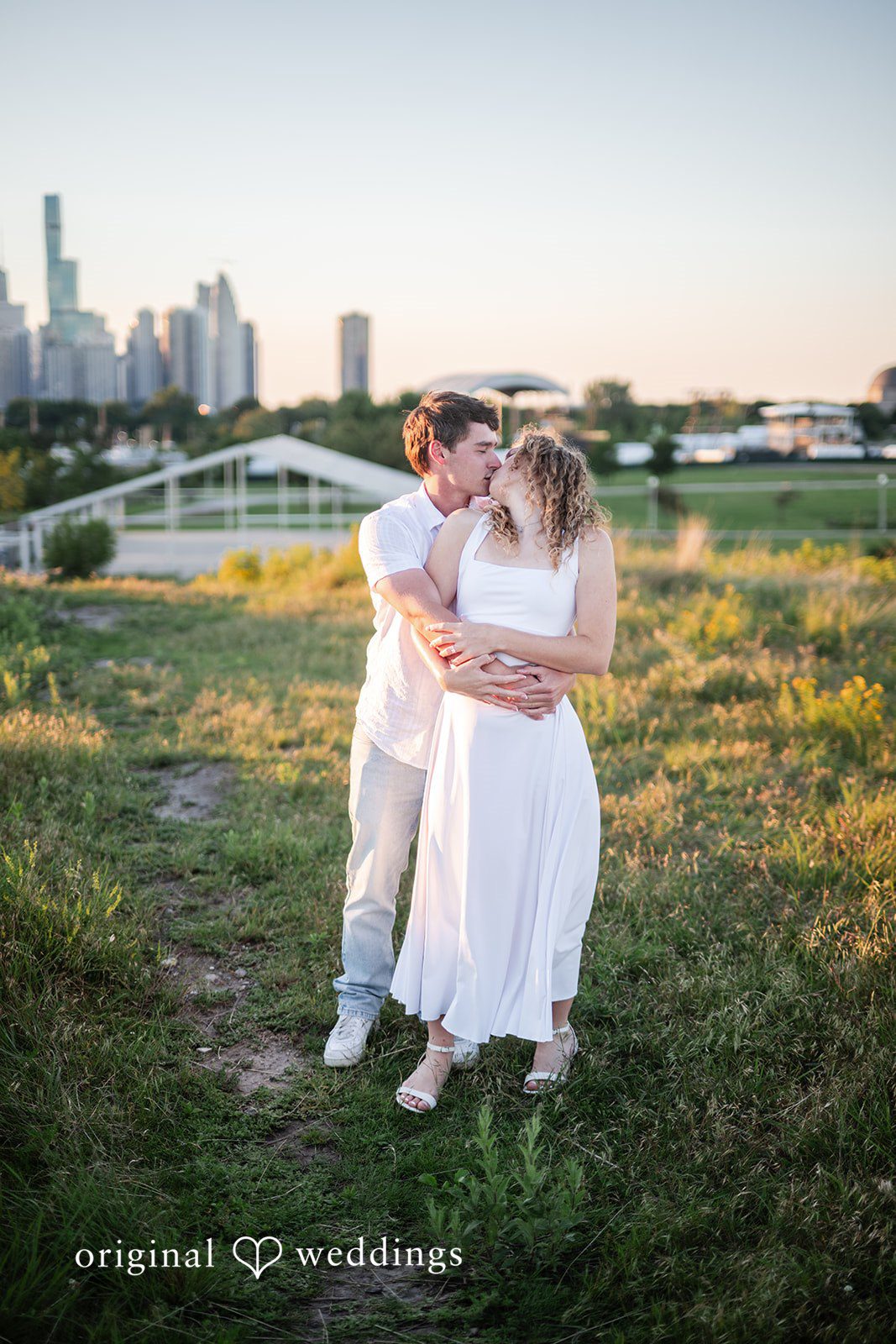 A man and a woman walking along a path winding through a grassy hill.