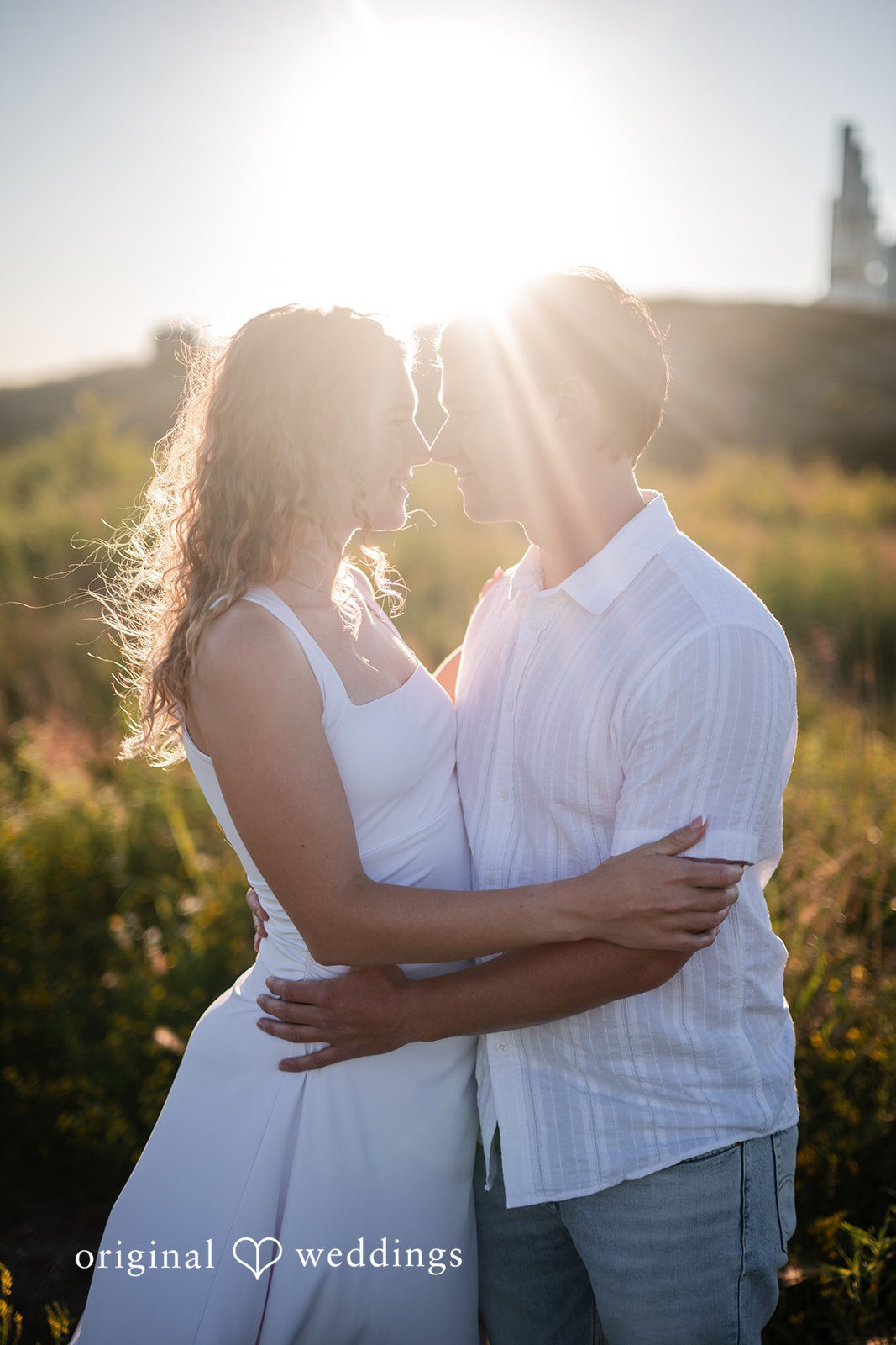 A man and a woman embracing each other against a bright sunset.