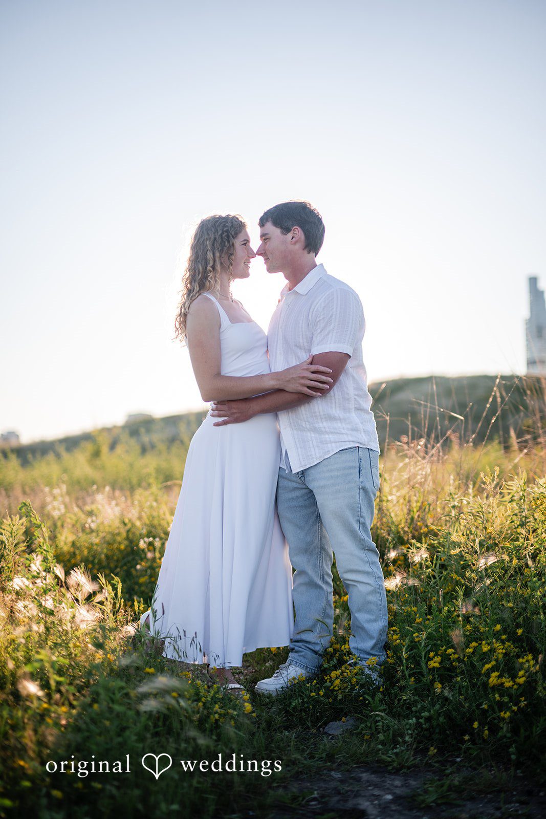 A man and a woman hugging in the middle of a grassy field.