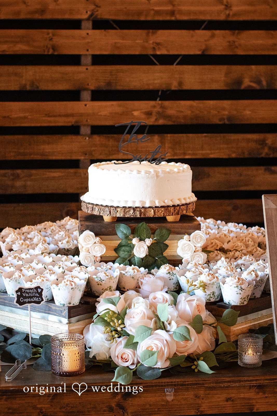 Madison + Ally Beautiful wedding cake surrounded by cupcakes candles and romantic floral arrangements