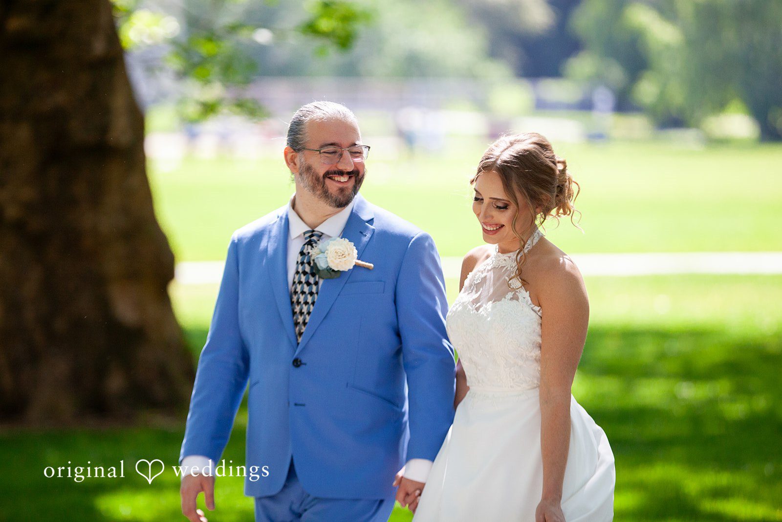 Sasha + Tom Bride and groom walking together while smiling at The Great Hall at Green Lake