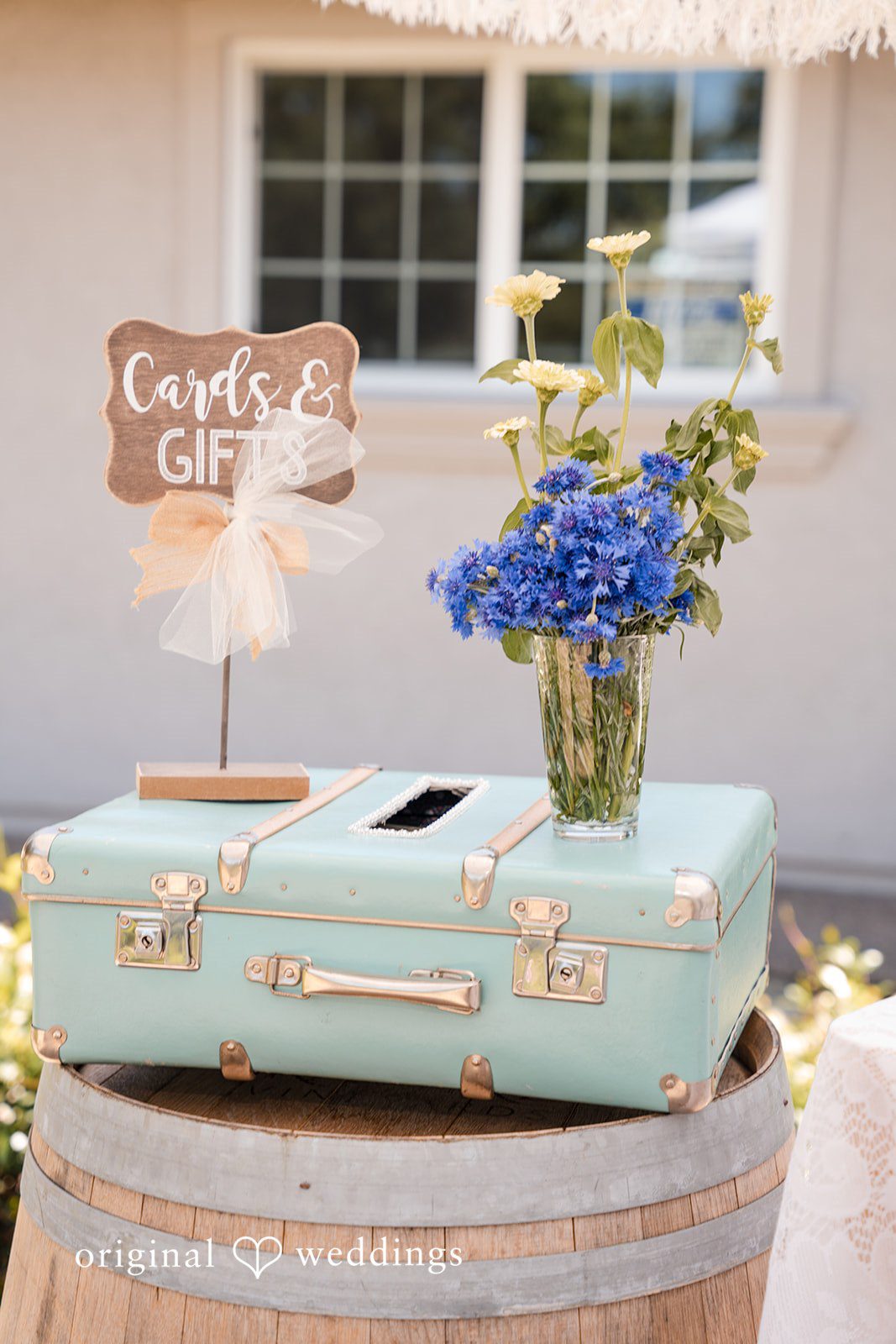 Avery + Ryan A vintage mint green suitcase styled as a card collection box next to blue flowers.