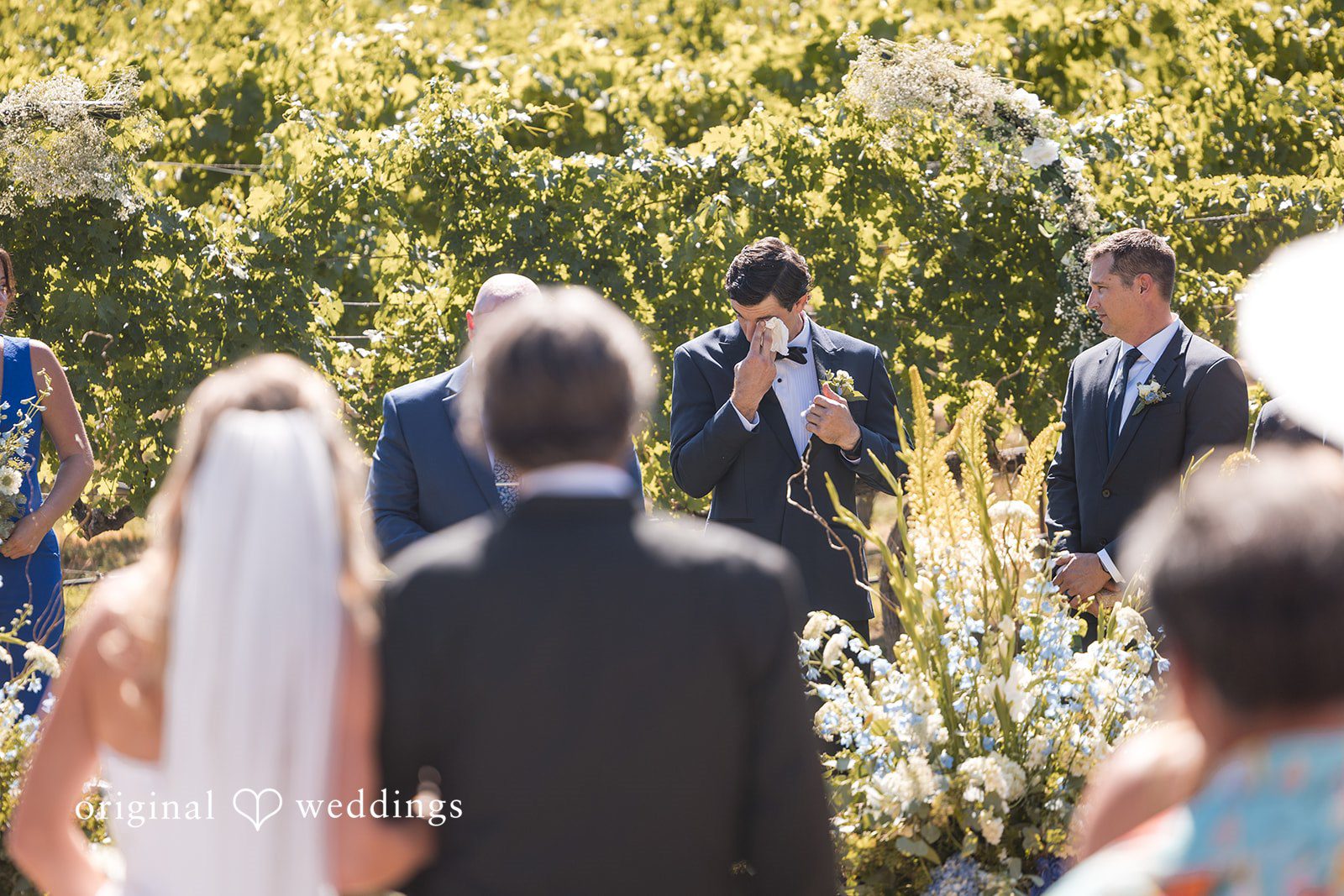 Avery + Ryan Guests watching the back of a bride and groom during a wedding ceremony.