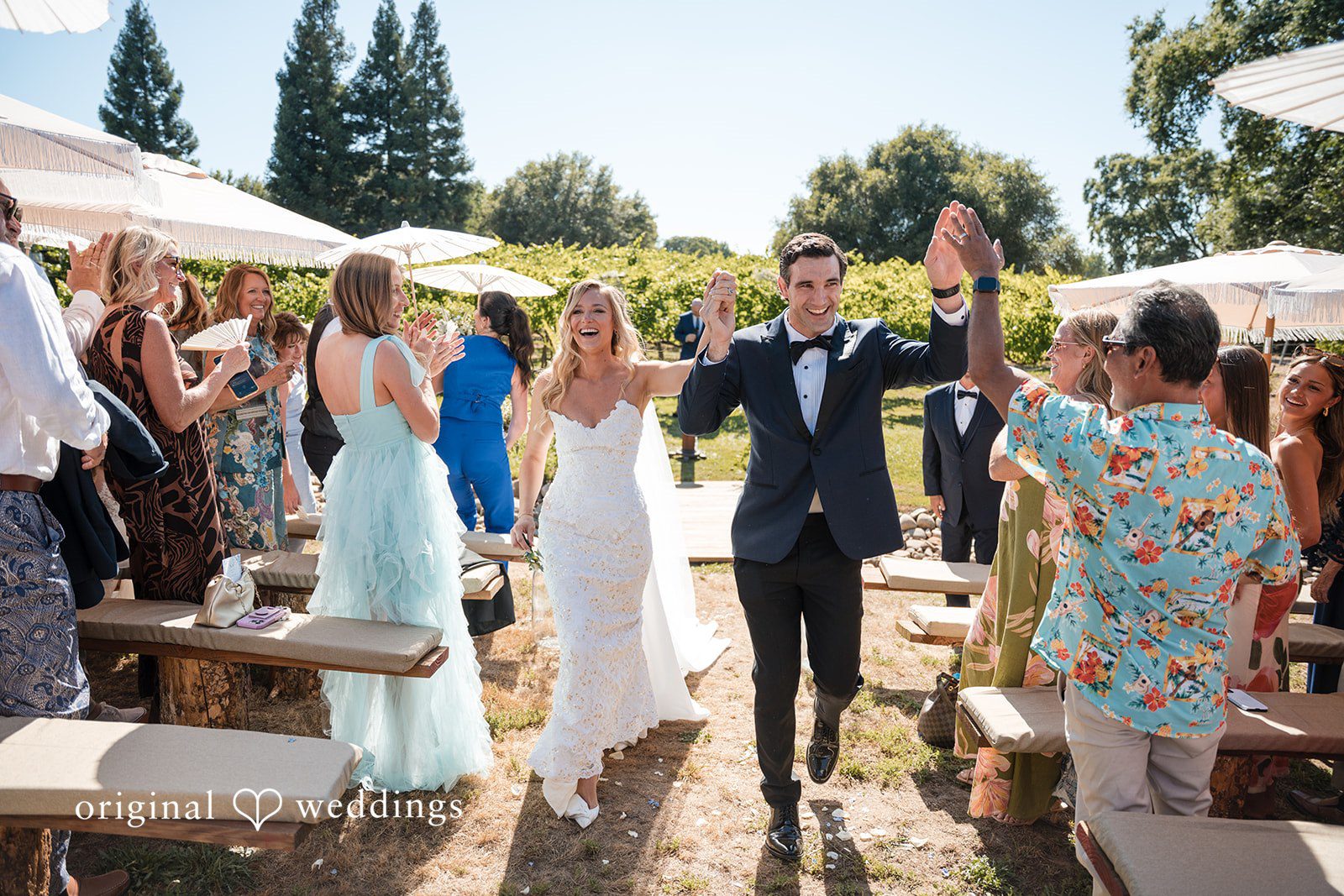 Avery + Ryan A newly married couple walking down the aisle while guests cheer.