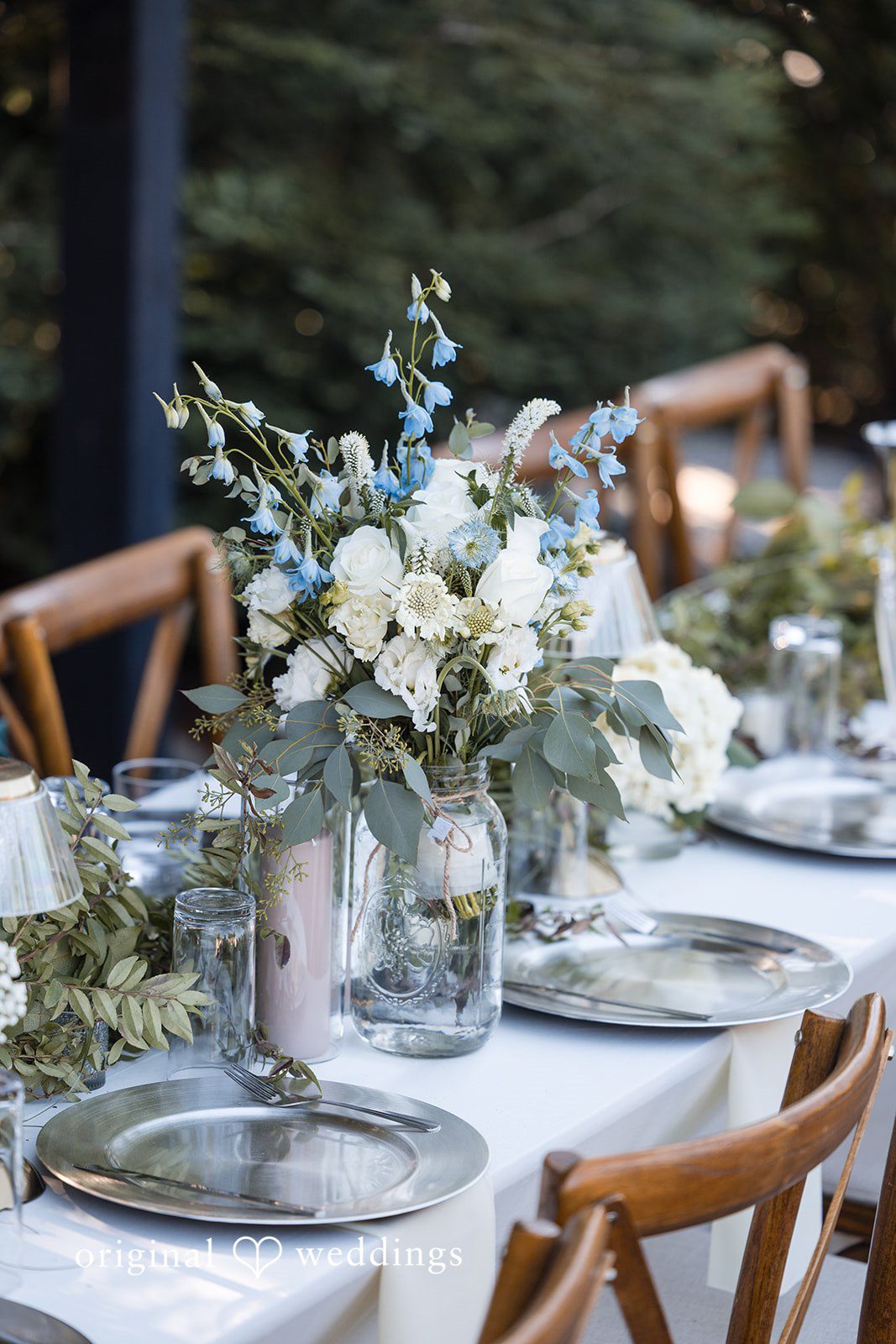 Avery + Ryan A wedding reception table decorated with a large white and green floral centerpiece.