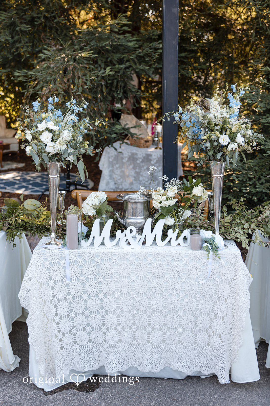 Avery + Ryan A sweetheart table dressed in a white lace tablecloth with a "Mr. & Mrs." sign.