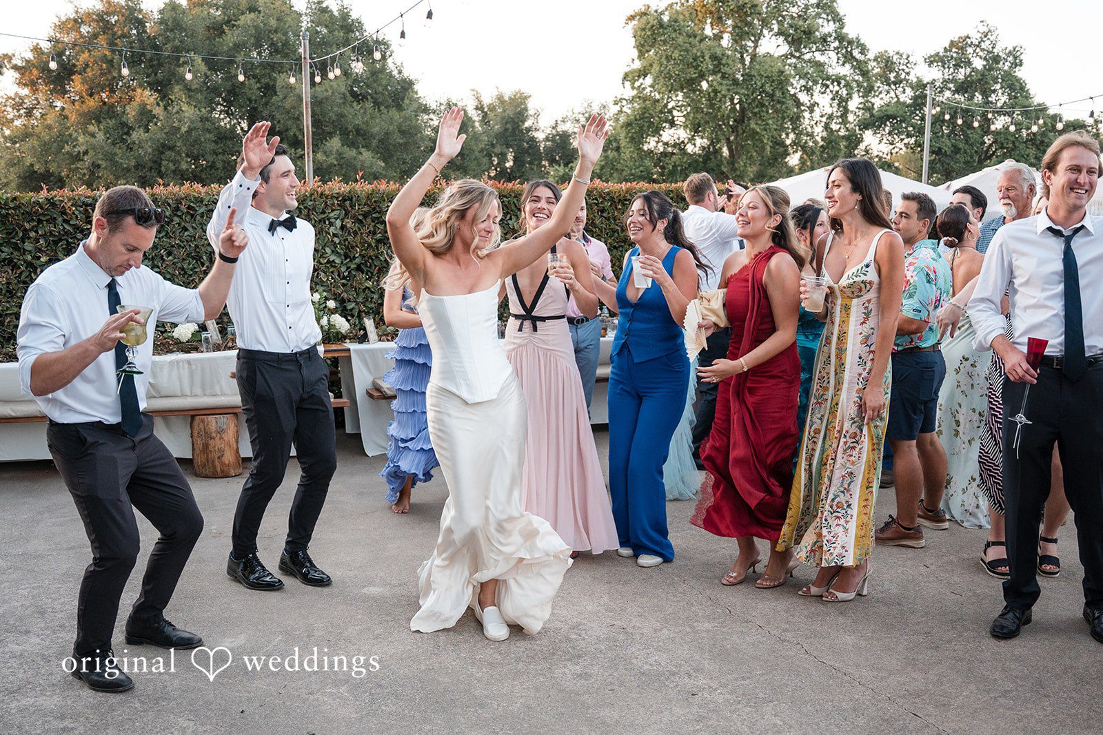 Avery + Ryan A bride dancing energetically with her wedding guests on an open-air dance floor.