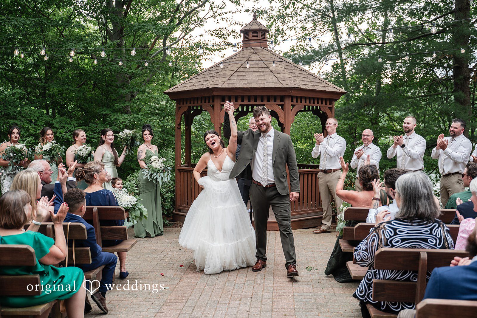 Newlyweds sharing a joyful walk together as family and friends celebrate nearby