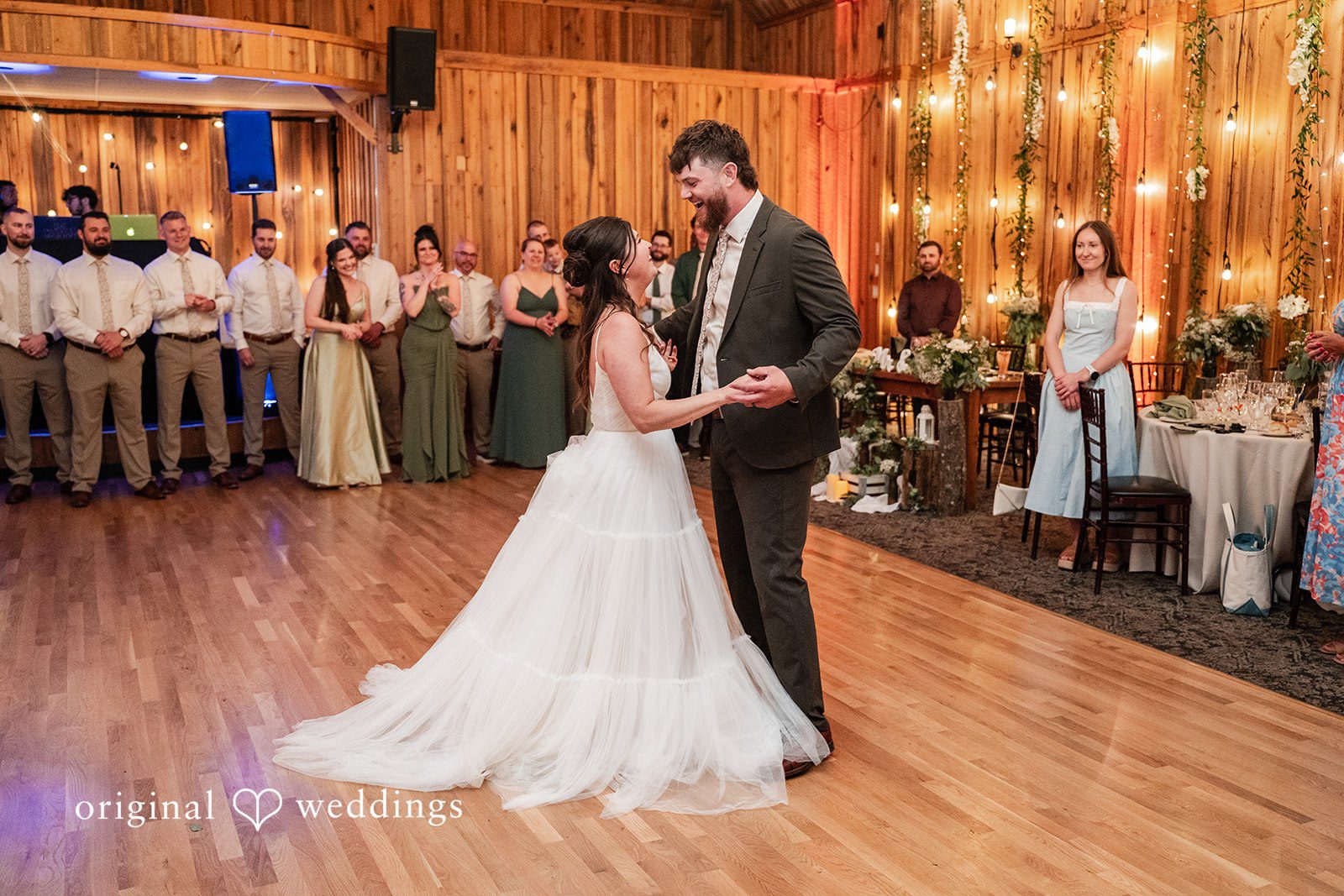 Bride and groom smiling at each other while dancing together.
