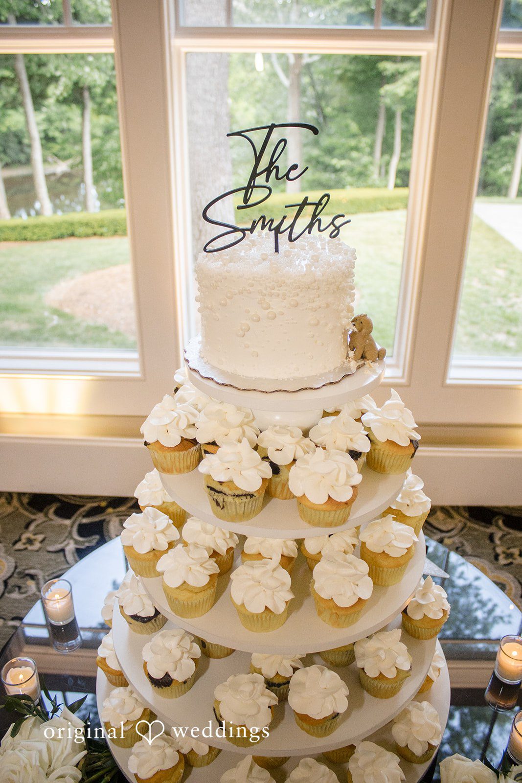 Kimberly + Jordan Beautiful white wedding cake surrounded by cupcakes and candlelight at The Riverview