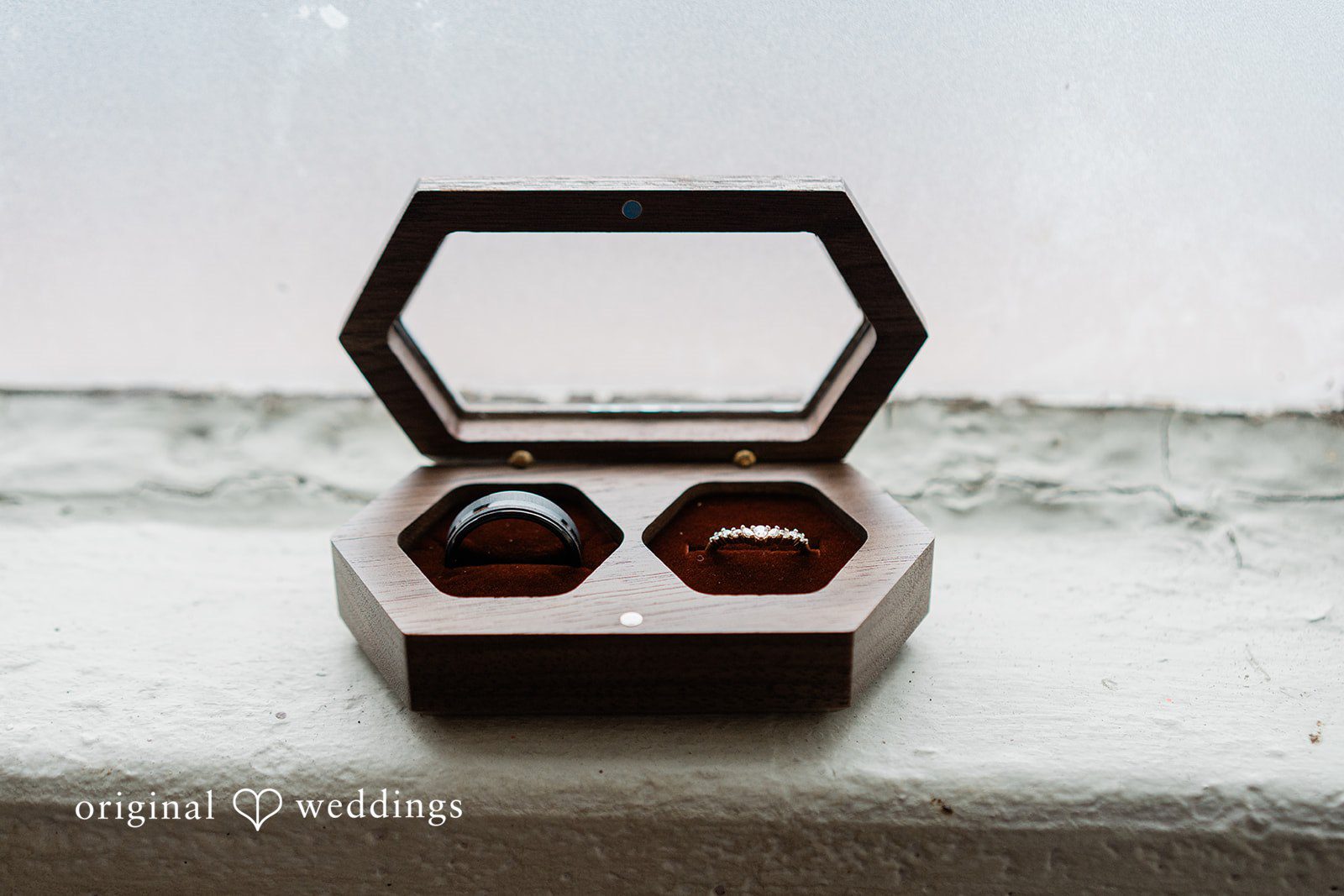 Madison + Malik Two wedding bands resting inside a geometric, hexagonal wooden ring box.