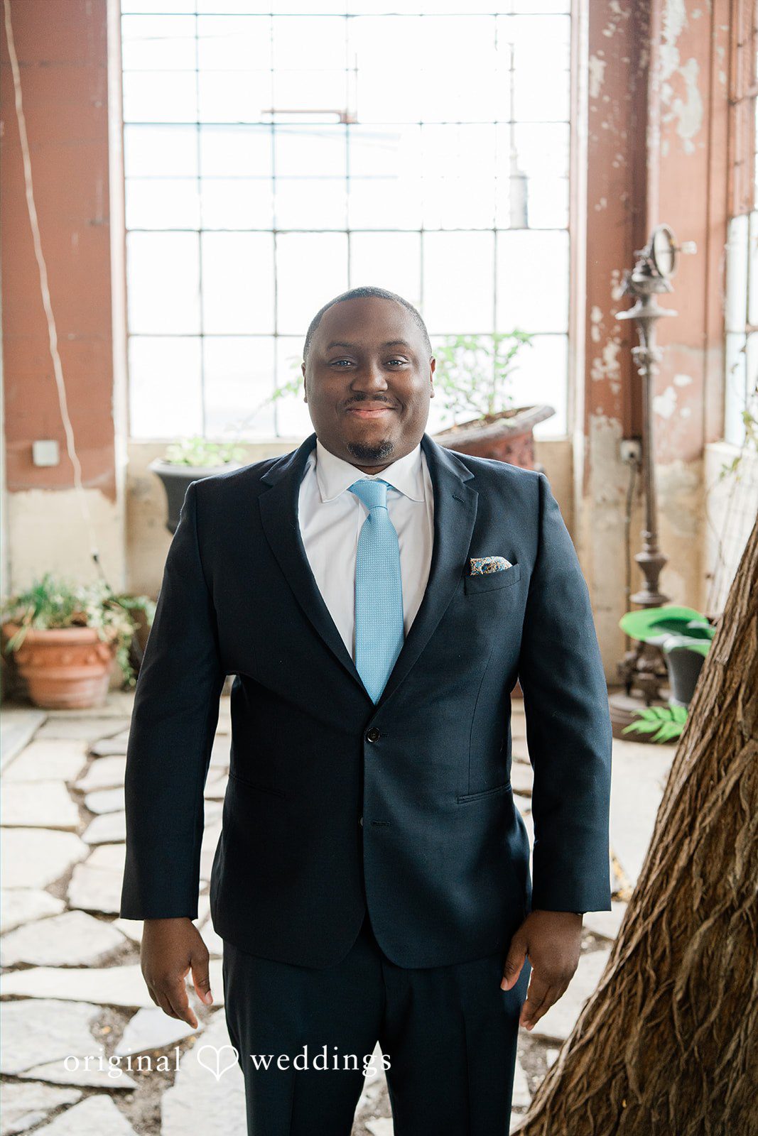 Madison + Malik A portrait of a groom wearing a dark suit, light blue tie.