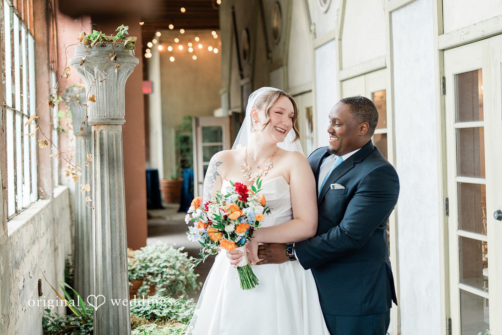 Madison + Malik A bride and groom smiling at each other while holding a colorful bouquet.