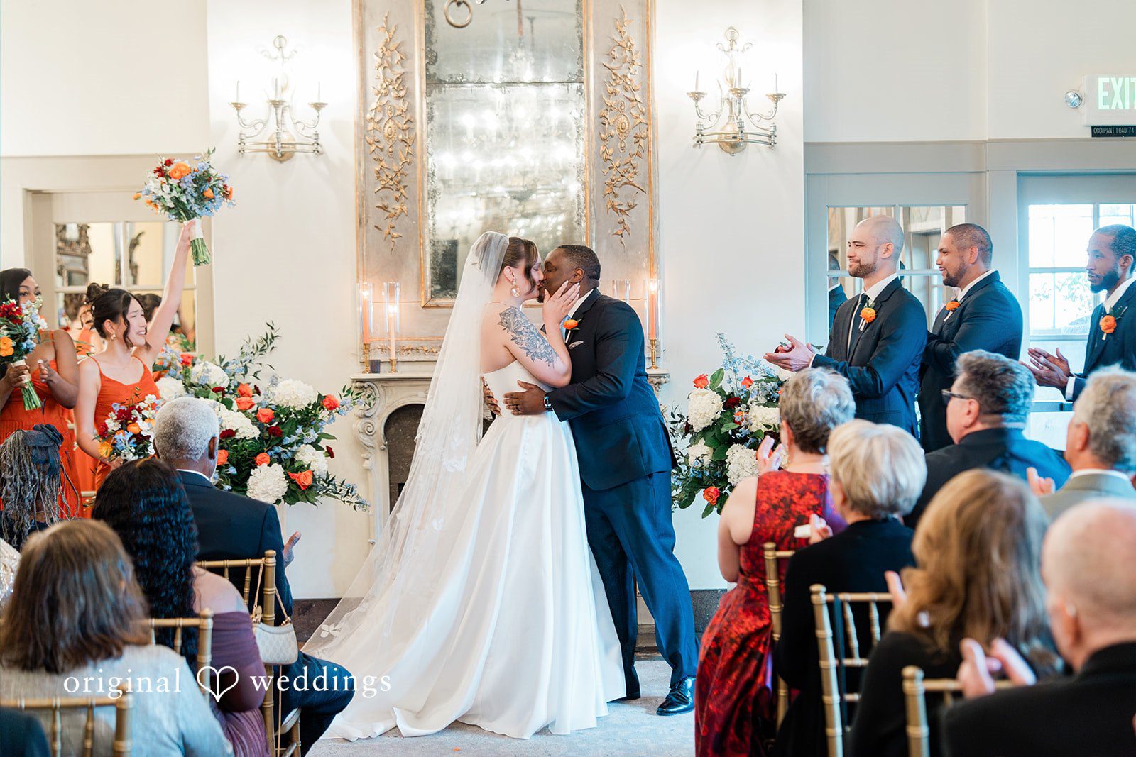 Madison + Malik Bride and groom sharing their first kiss at the altar in front of seated guests.