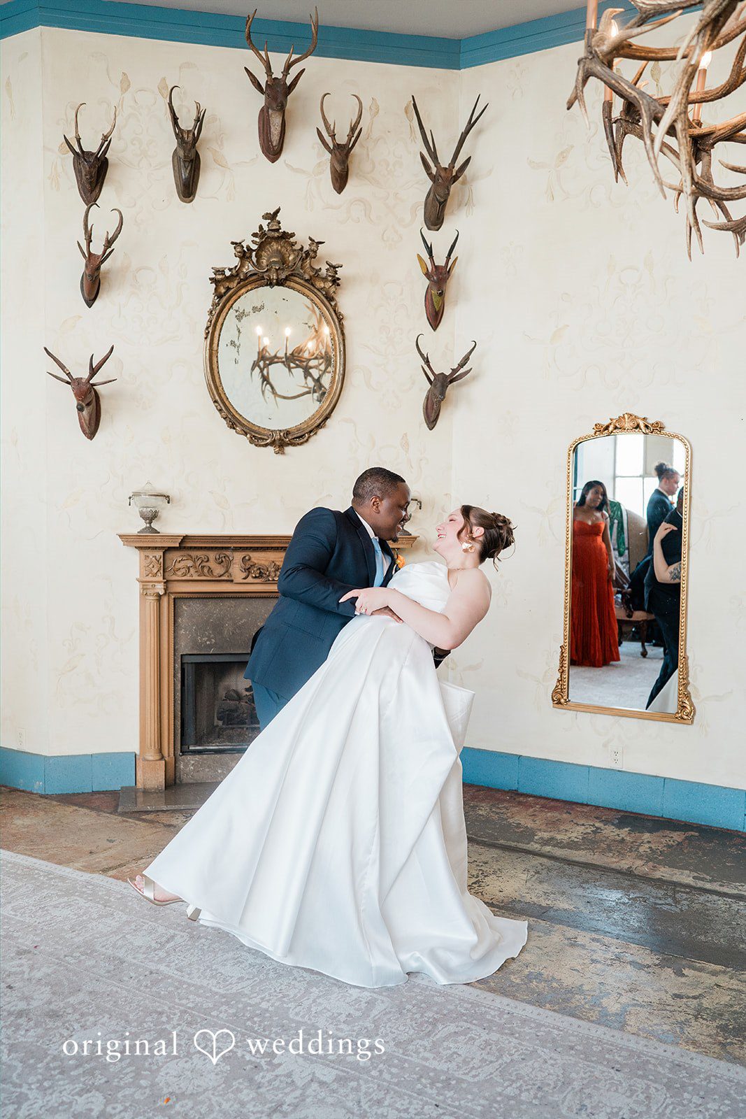 Madison + Malik A couple dipping and kissing in a room decorated with deer antlers.