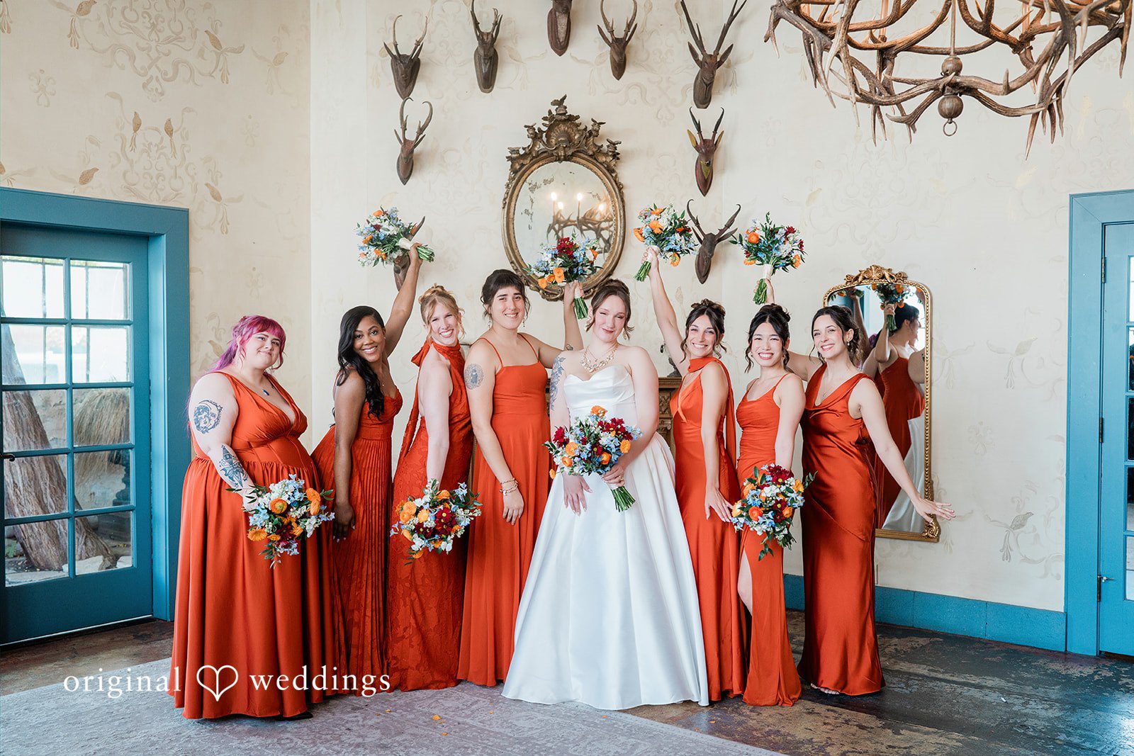 Madison + Malik A full-length portrait of a bride with bridesmaids in orange dresses.
