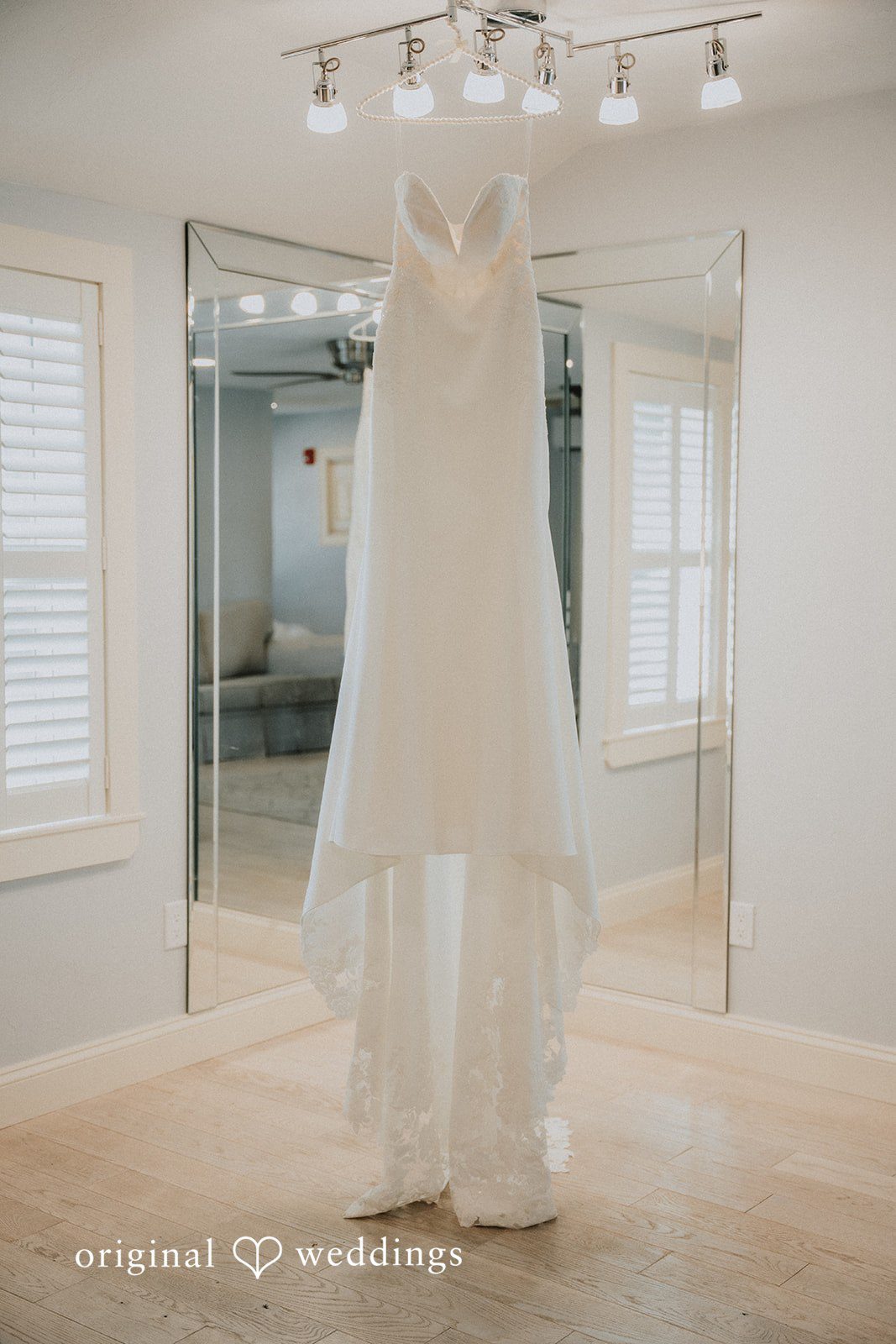 Kaylee + Raul A white wedding dress hanging in a bright, modern room with wooden floors.