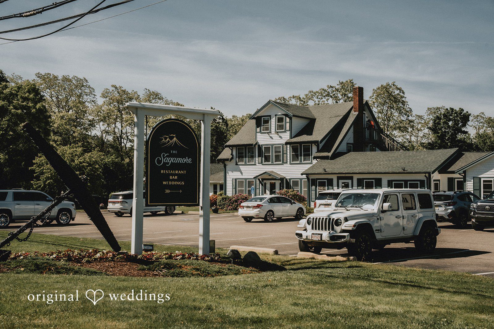 Kaylee + Raul A wedding venue entrance with a black sign and a white vintage truck parked nearby.