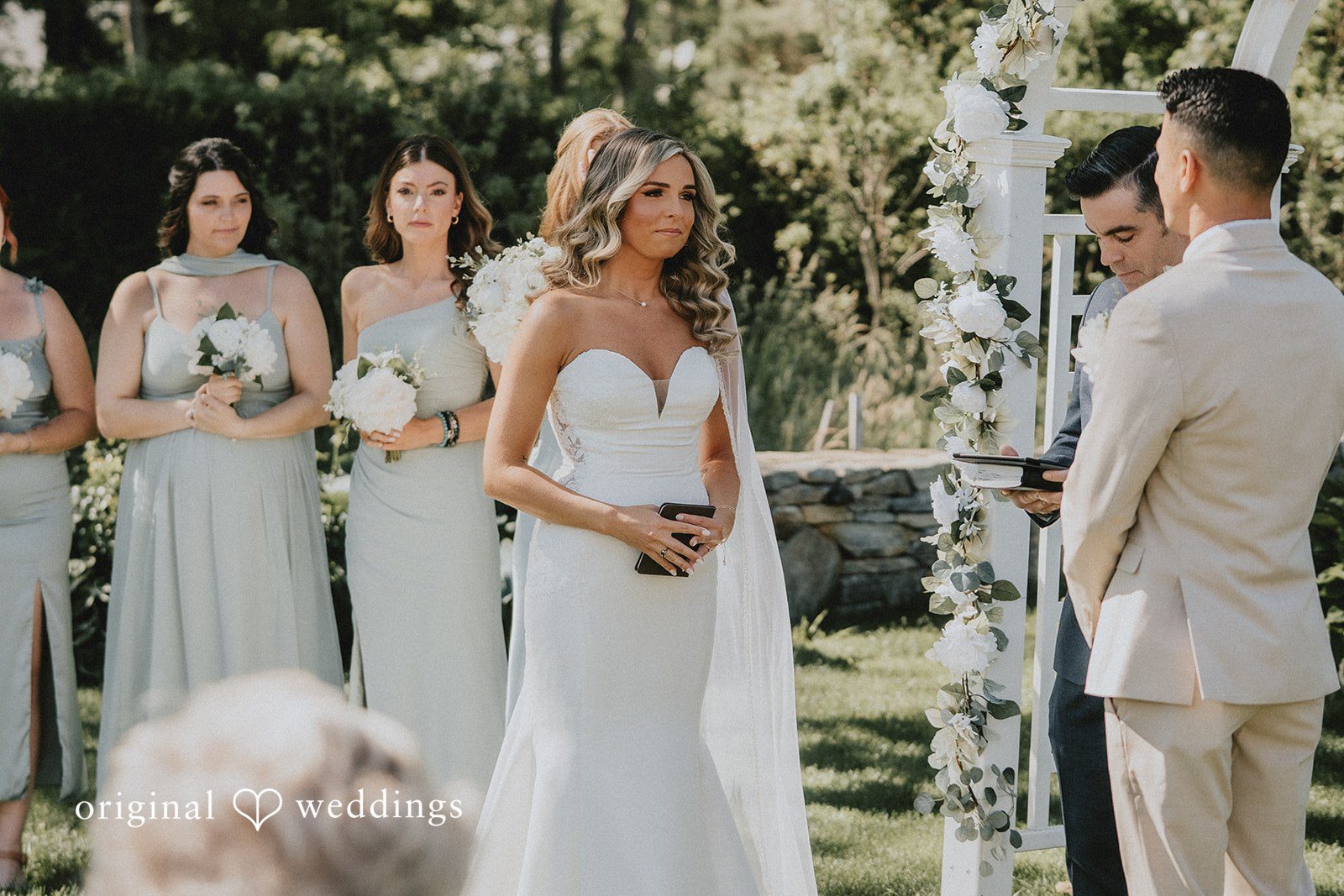 Kaylee + Raul A bride standing at the altar with her bridesmaids in light blue dresses nearby.