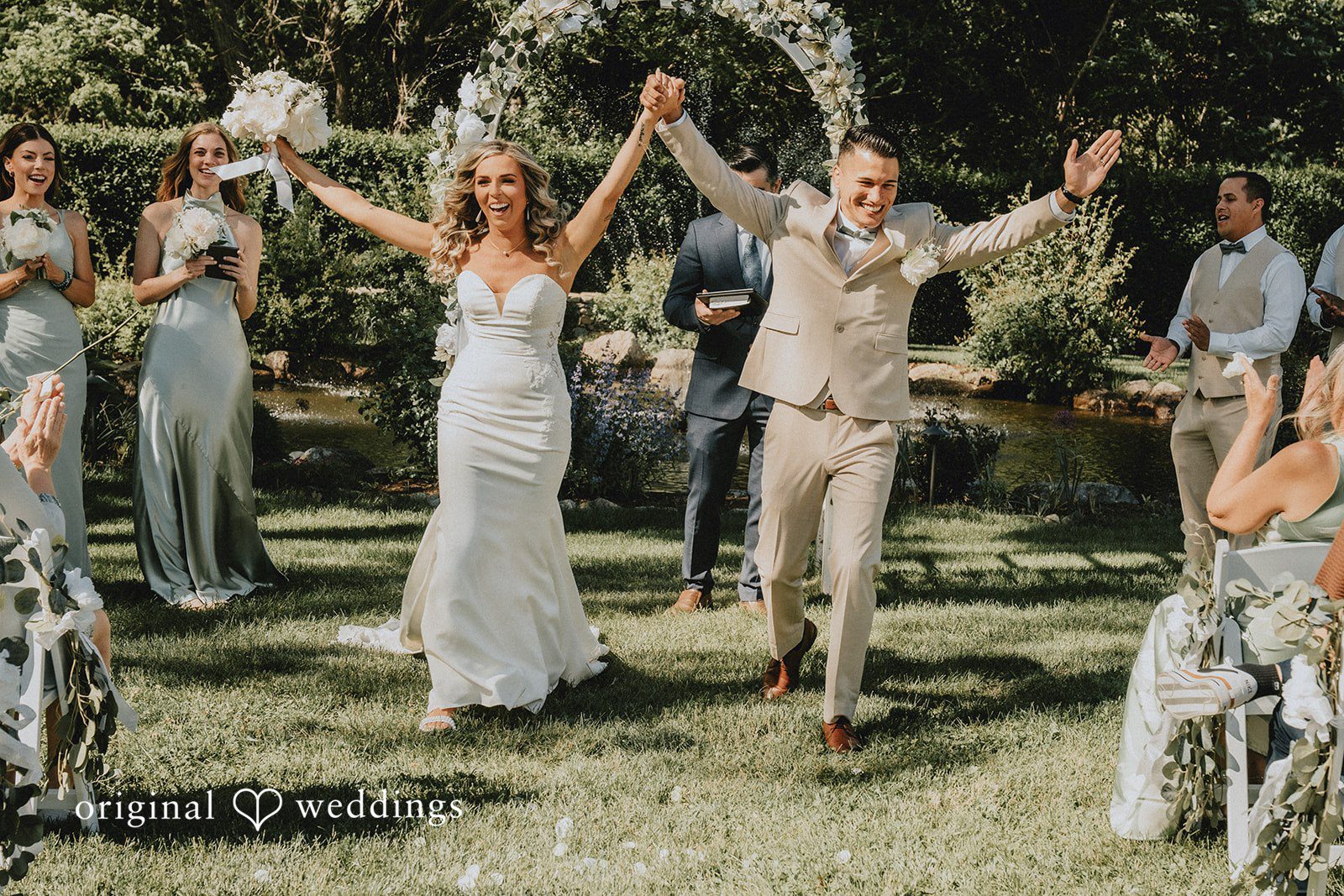 Kaylee + Raul A newlywed couple celebrating with raised arms while walking down the aisle.