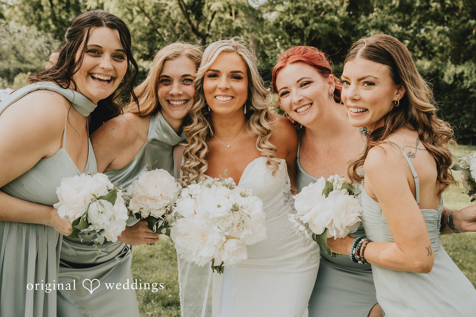 Kaylee + Raul A bride posing and smiling alongside four bridesmaids dressed in light blue gowns.