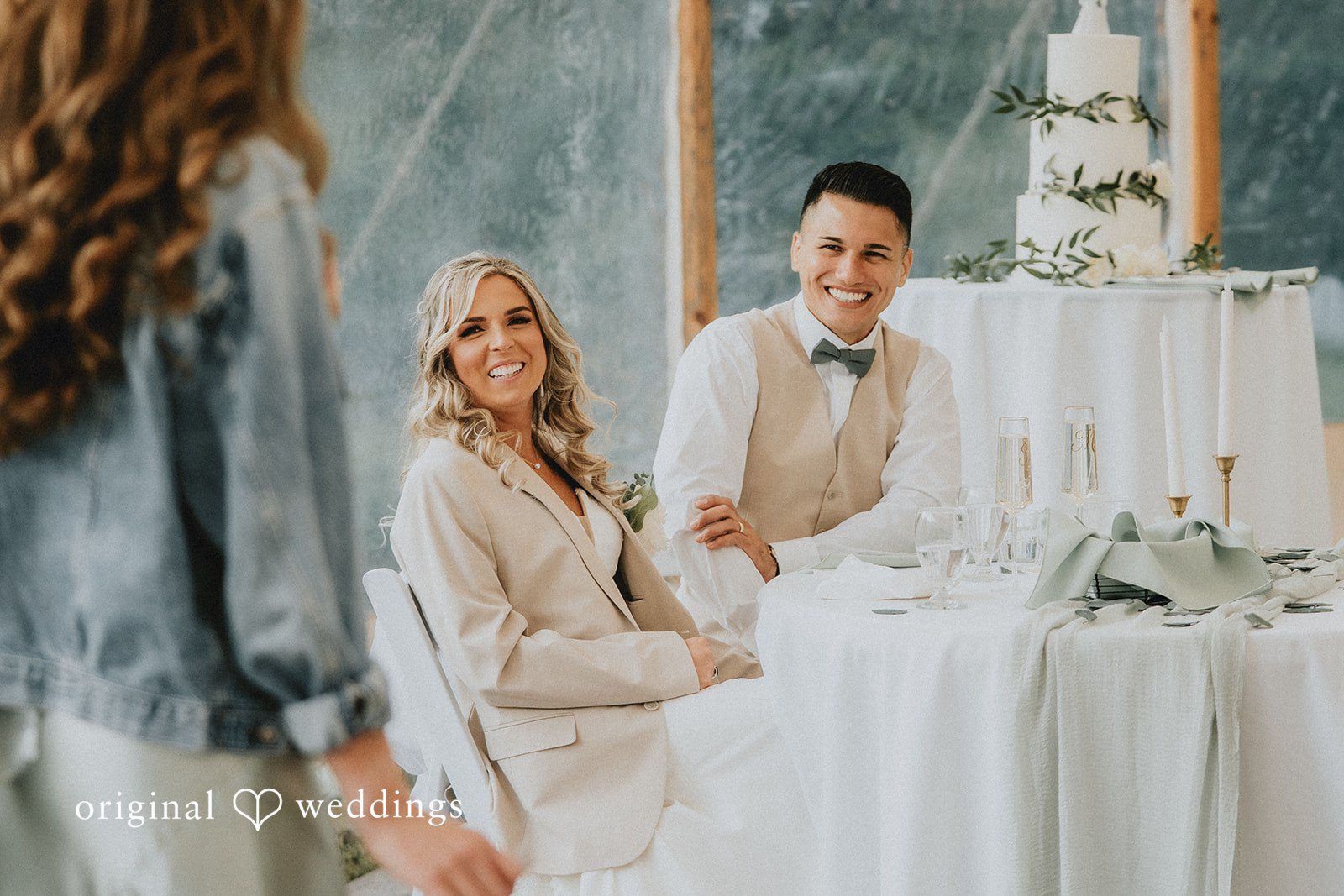 Kaylee + Raul A bride and groom sitting together at a decorated wedding reception table.