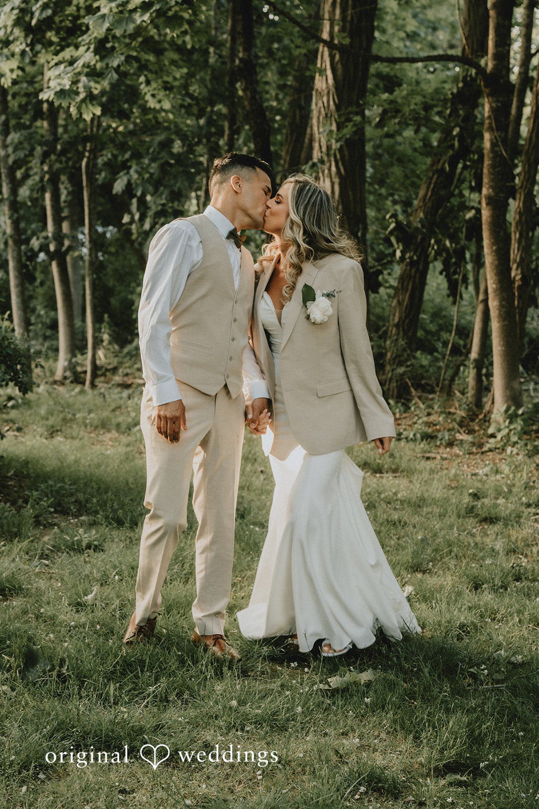 Kaylee + Raul A bride and groom walking together through a wooded area.
