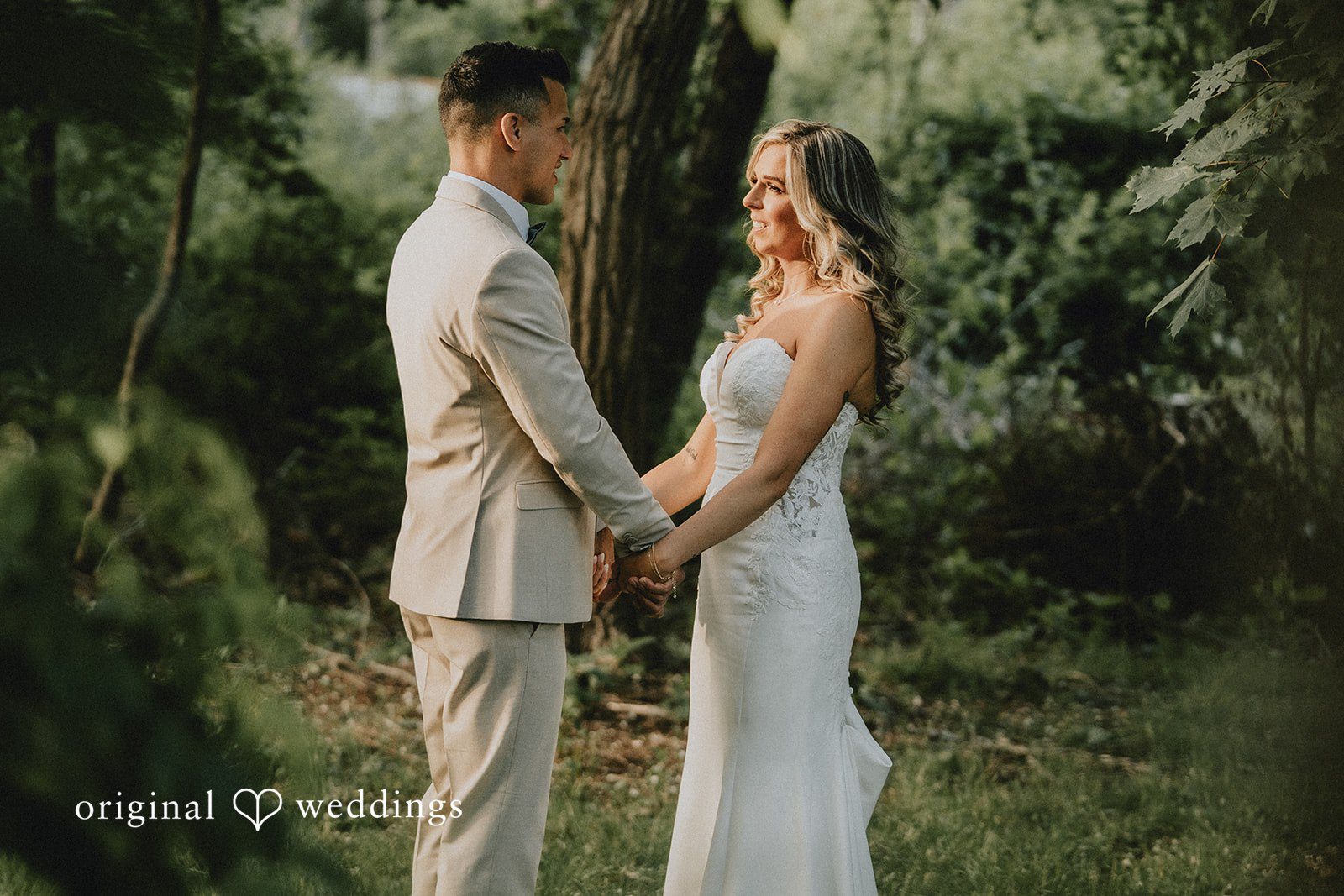 Kaylee + Raul A bride and groom holding hands while standing opposite each other in a forest.