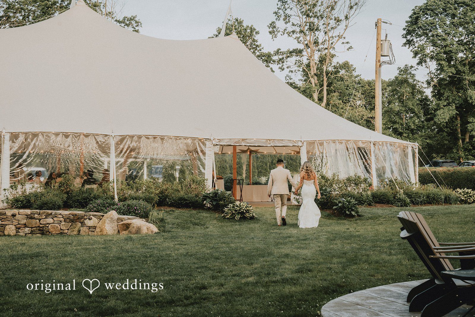 Kaylee + Raul A large white wedding tent pitched on a field near a line of trees.