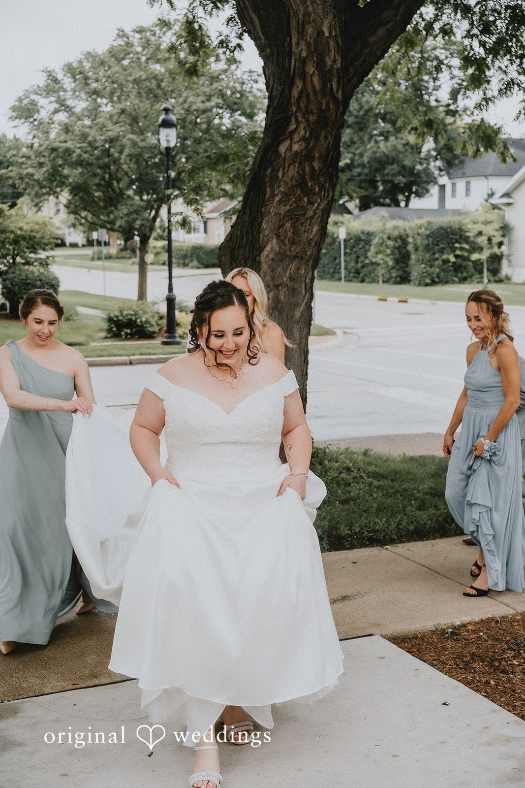 Kevin + Brooke Bridesmaid holding the gown of bride while walking at The Seville