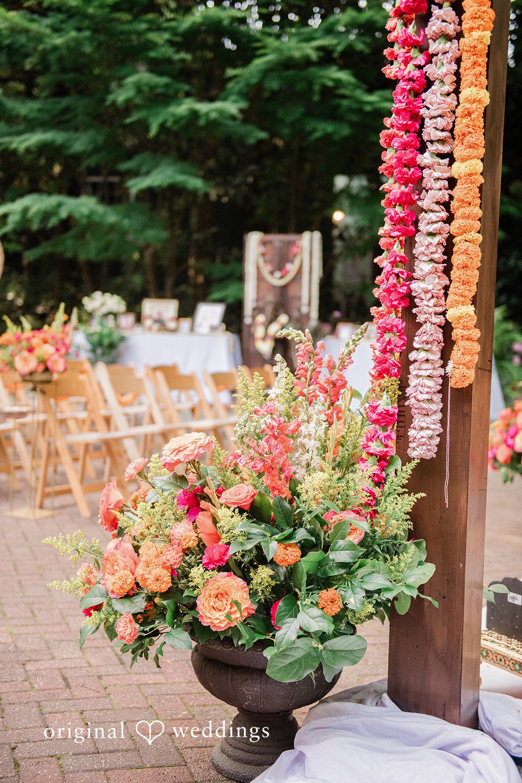 Sonya + Akshaya A vibrant orange flower arrangement displayed in a rustic clay pot.