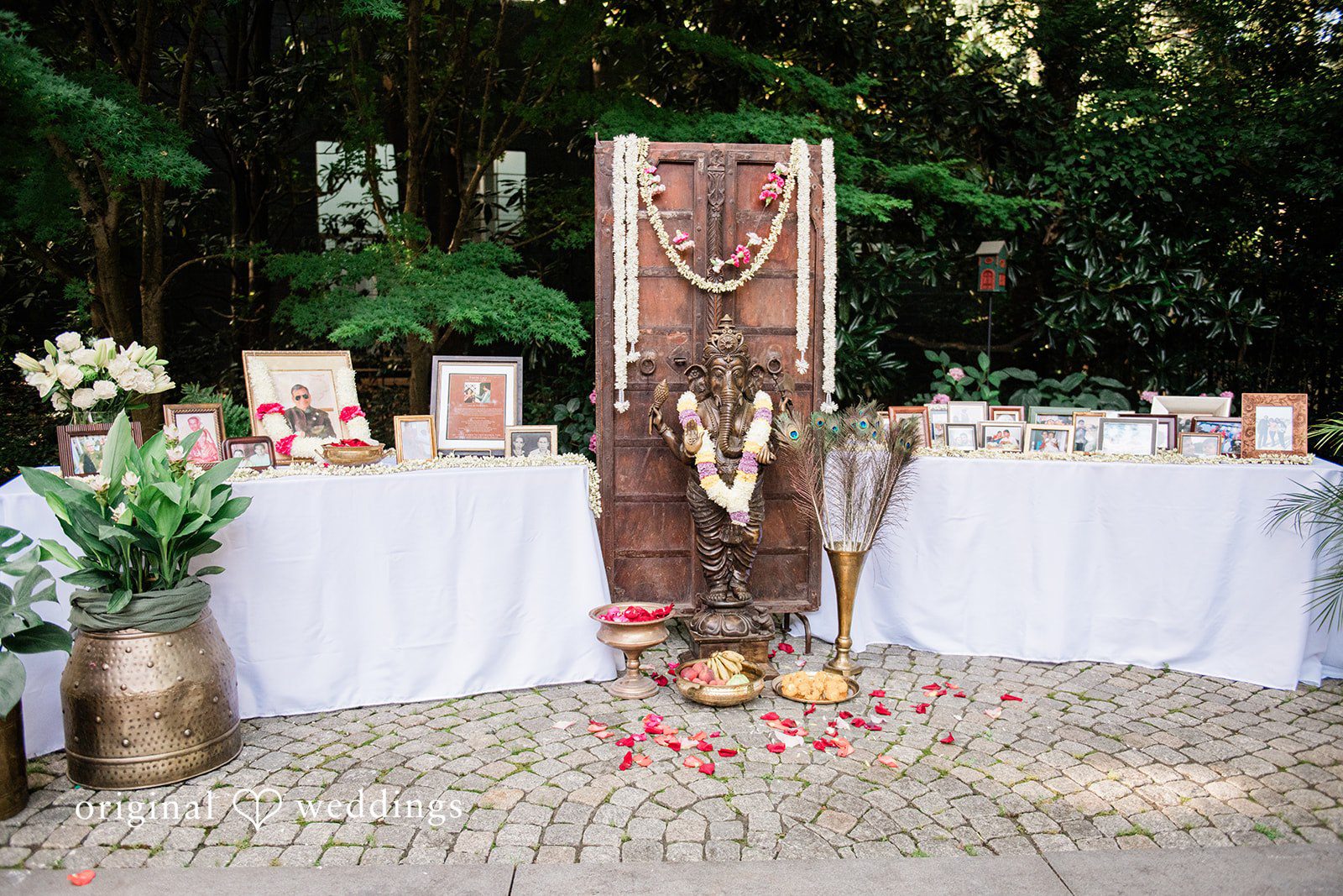 Sonya + Akshaya A decorated wedding welcome table featuring a wooden sign and floral arrangements.