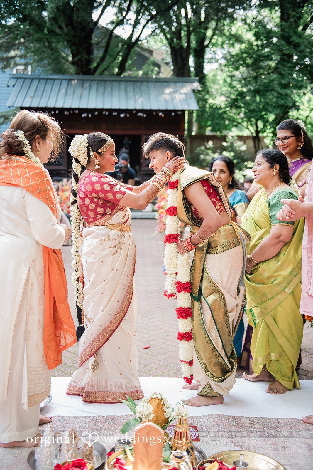 Sonya + Akshaya A couple performing a traditional ritual surrounded by family members.
